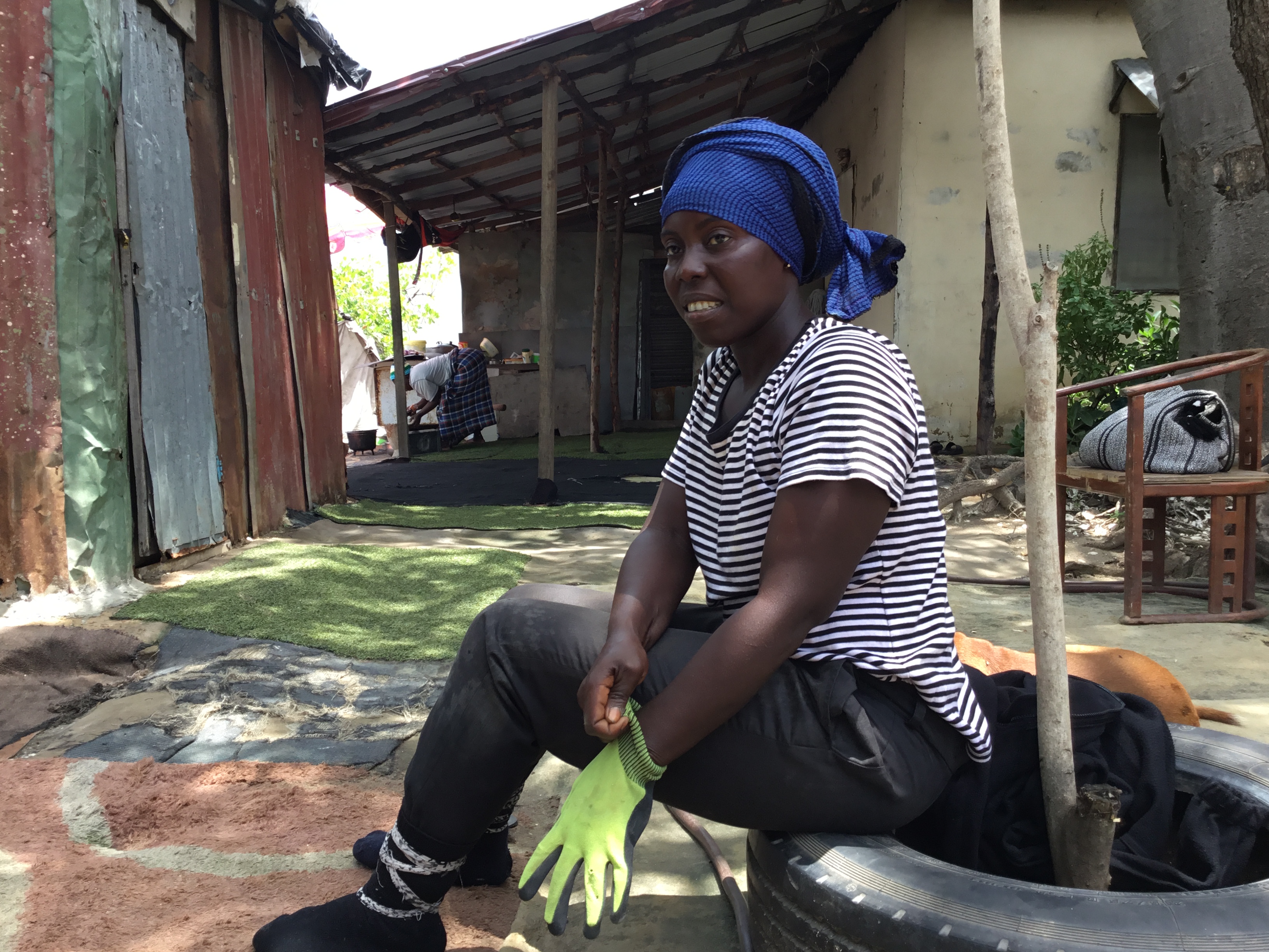 Fatou prepares for a day of crab harvesting, pulling on her gloves before venturing into the mangrove forest