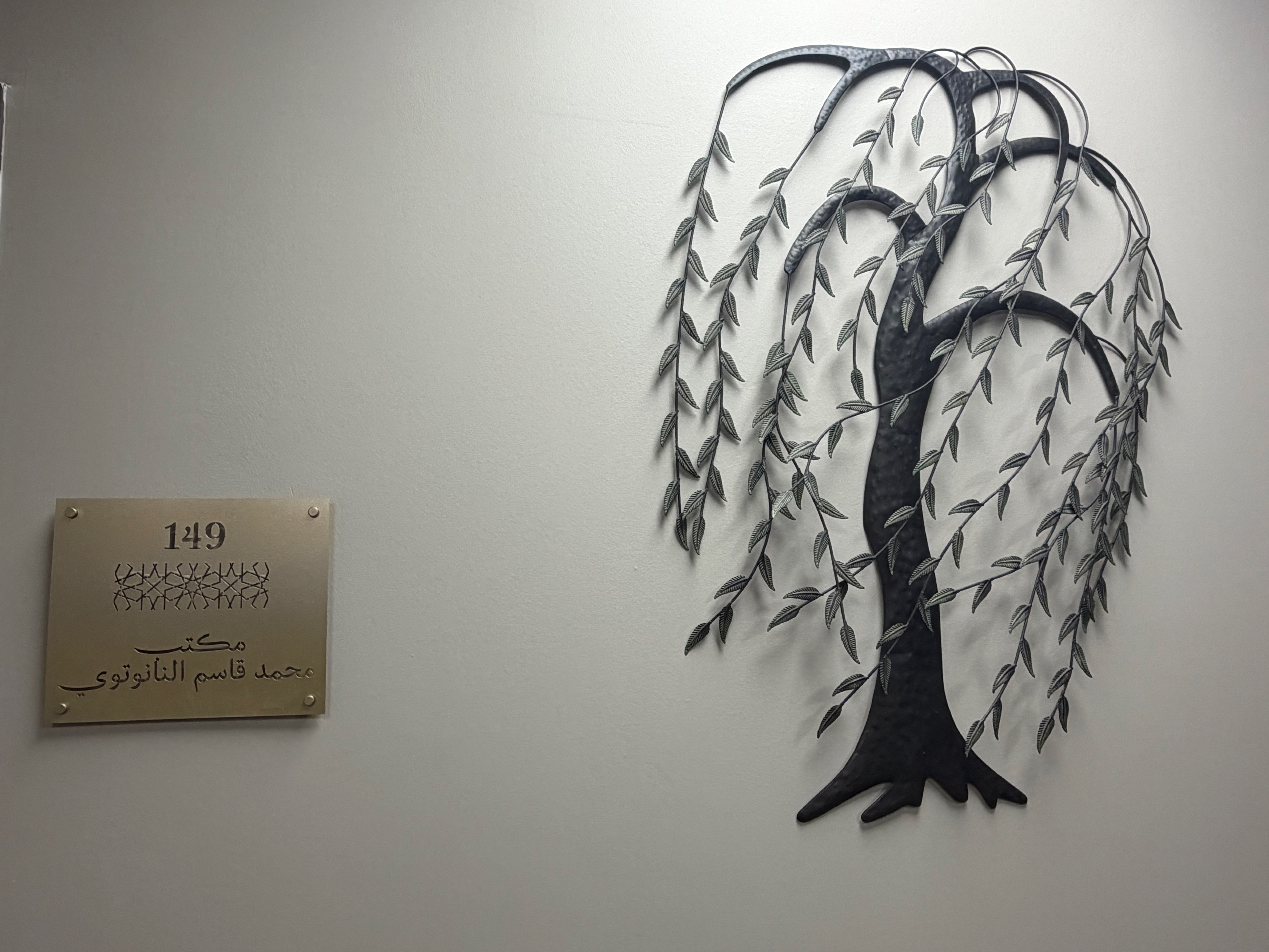 A plaque honouring Mawlana Mohammed Qasim Nanautavi sits beside a wrought iron willow tree at Darul Qasim in Chicago. The willow represents the search for knowledge that lies beneath the surface