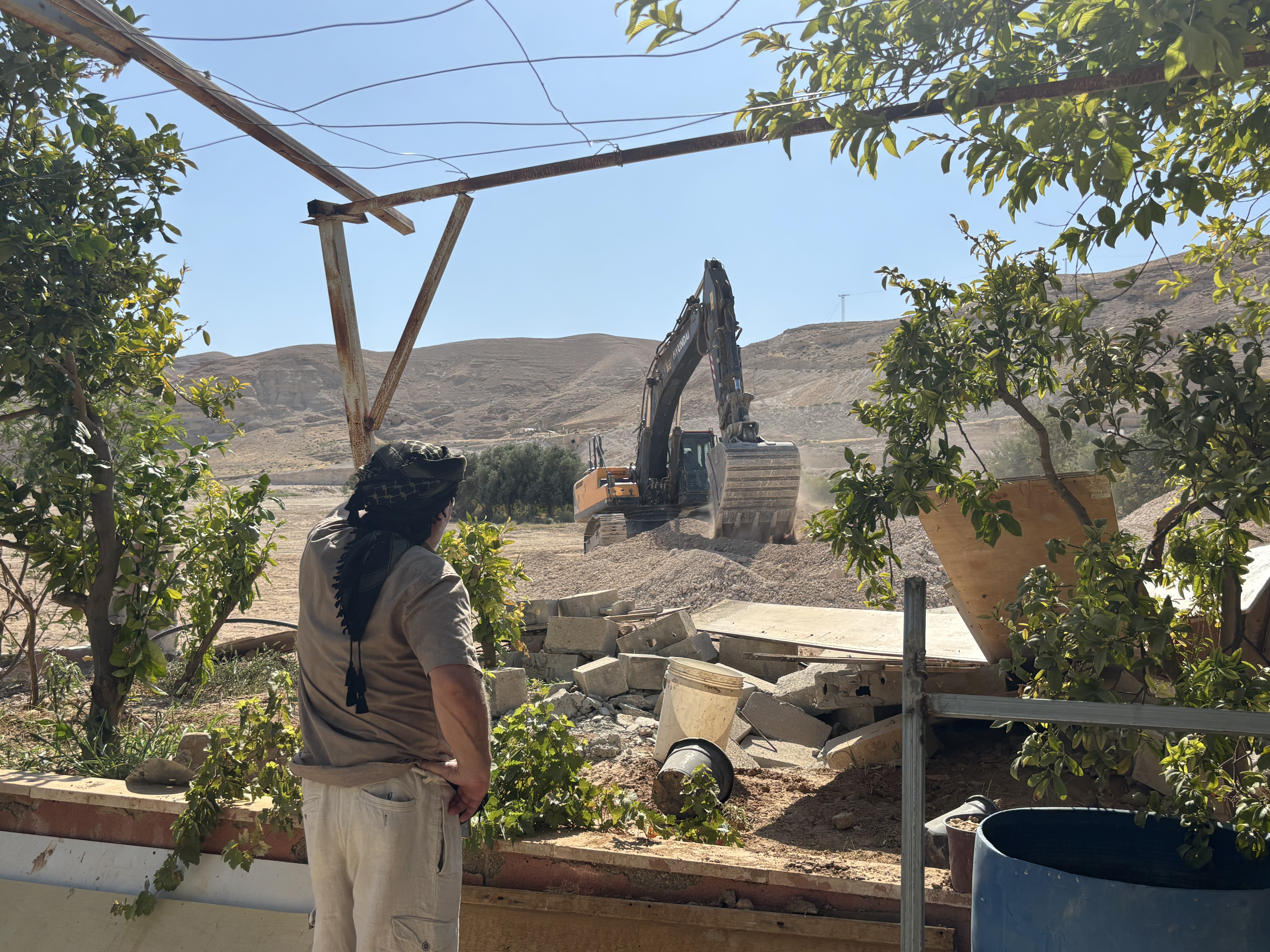 Palestinian in Ein al-Duyuk sees settler bulldozer furthering damage in yard [Courtesy of Unarmed Civilian Protection in Palestine]