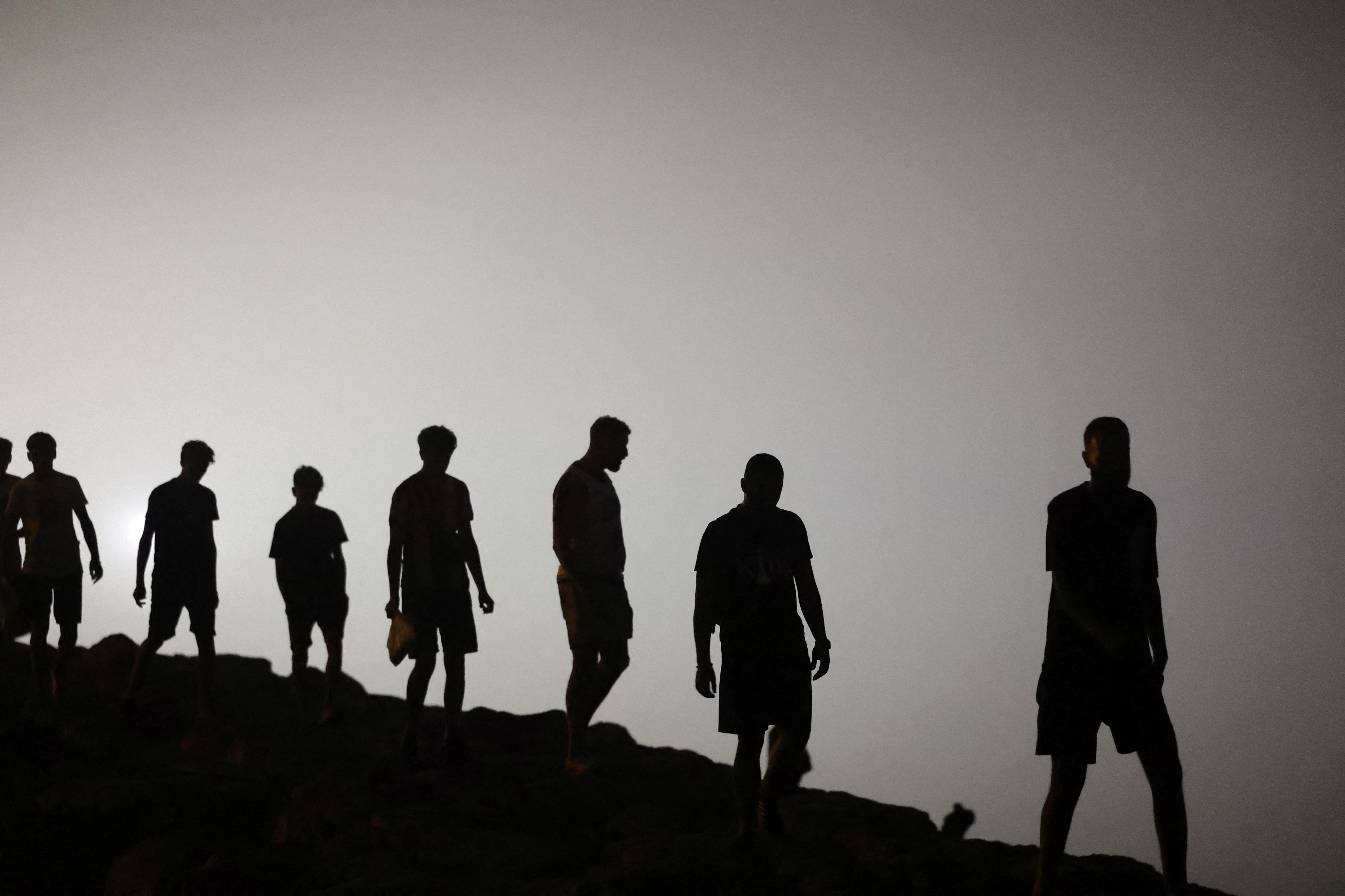 Migrants walk towards the Fnideq region in northern Morocco after leaving Spain's North African enclave of Ceuta near the town of Fnideq, on the Morocco-Spain border, following an attempted to cross at the Bab Sebta border crossing, on the Morocco-Spain border on August 1, 2026.