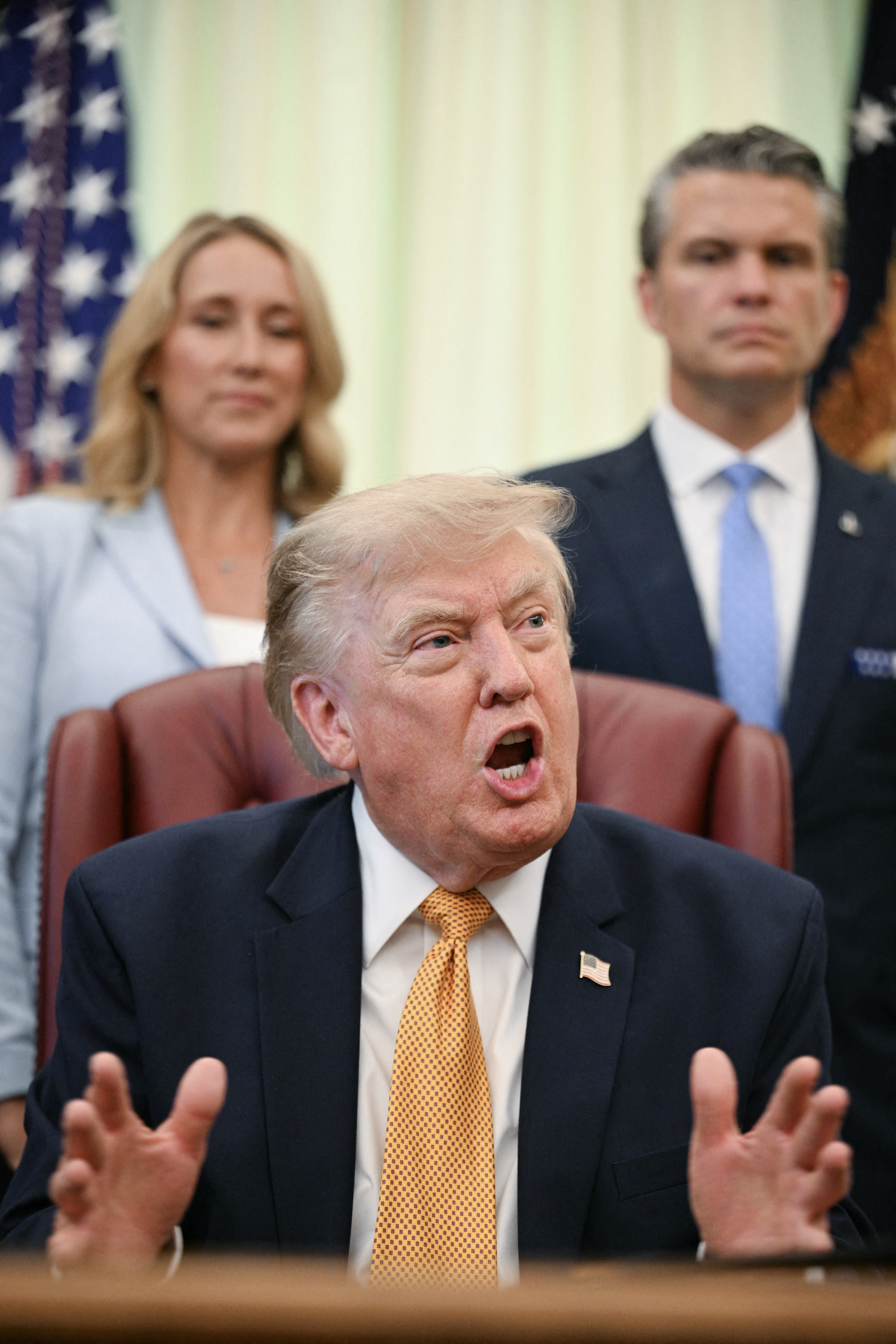US President Donald Trump speaks after signing an executive order in the Oval Office of the White House in Washington, DC, on August 3, 2026. Also pictured, Defense Secretary Pete Hegseth (R) and his wife Jennifer Hegseth (L).