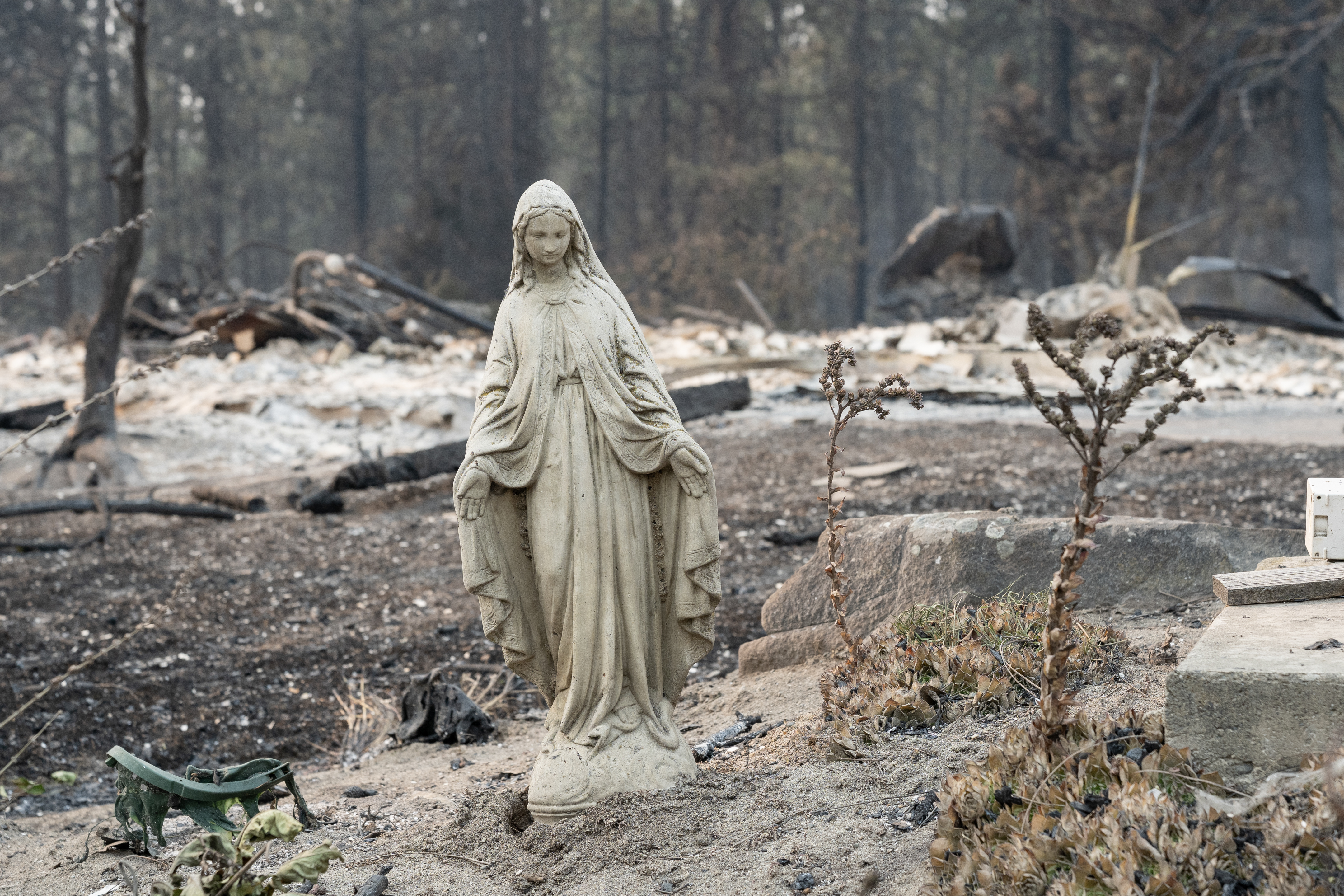 A Virgin Mary statue remains untouched in front of a burned out residential home in the Balboa neighborhood of Spokane, Washington, on August 2, 2026.