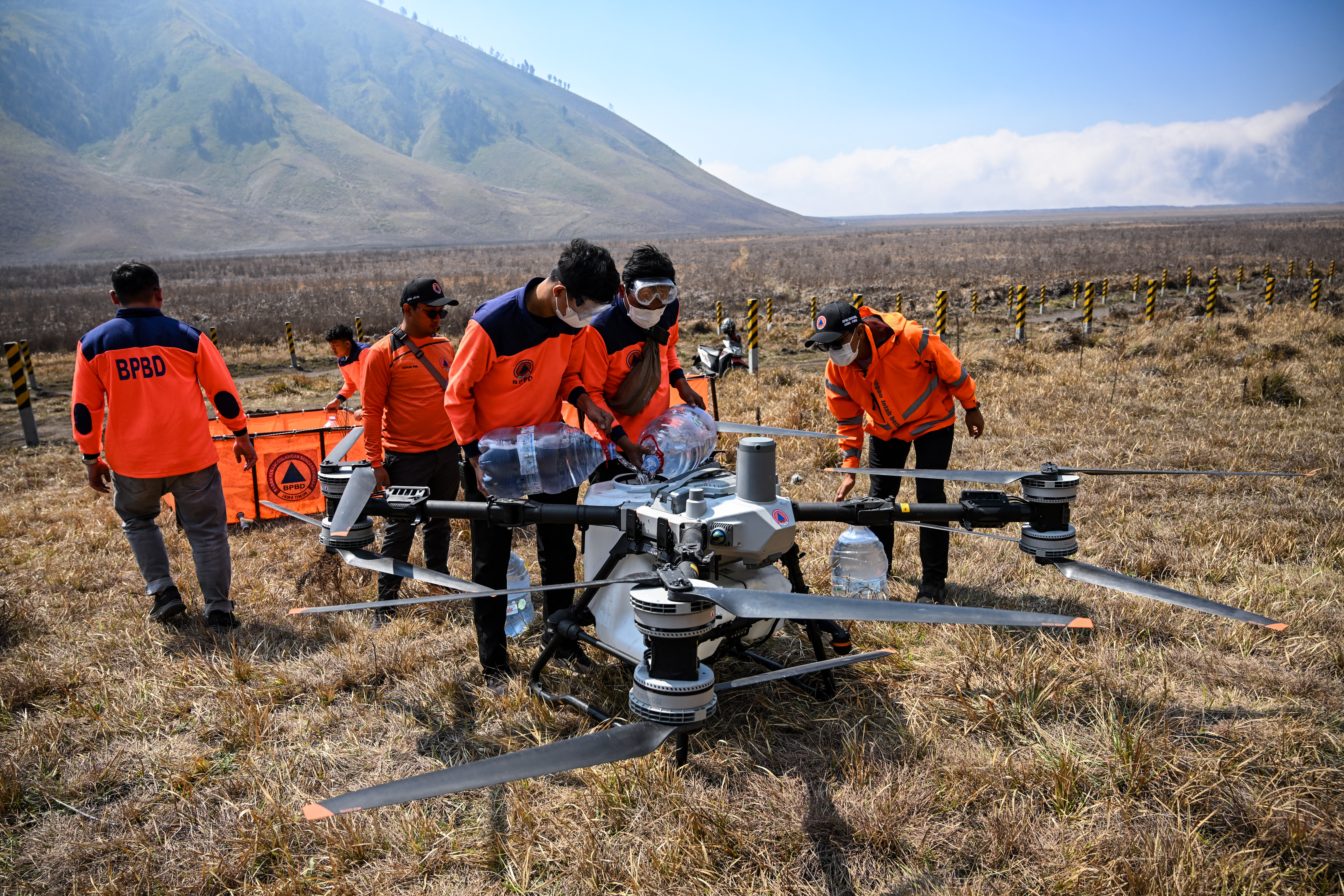 TOPSHOT - Officials from the East Java Provincial Disaster Management Agency fill a drone’s water tank to battle a wildfire in the Bromo Tengger Semeru National Park near Mount Bromo in Probolinggo, East Java province on August 6, 2026. (Photo by JUNI KRISWANTO / AFP)