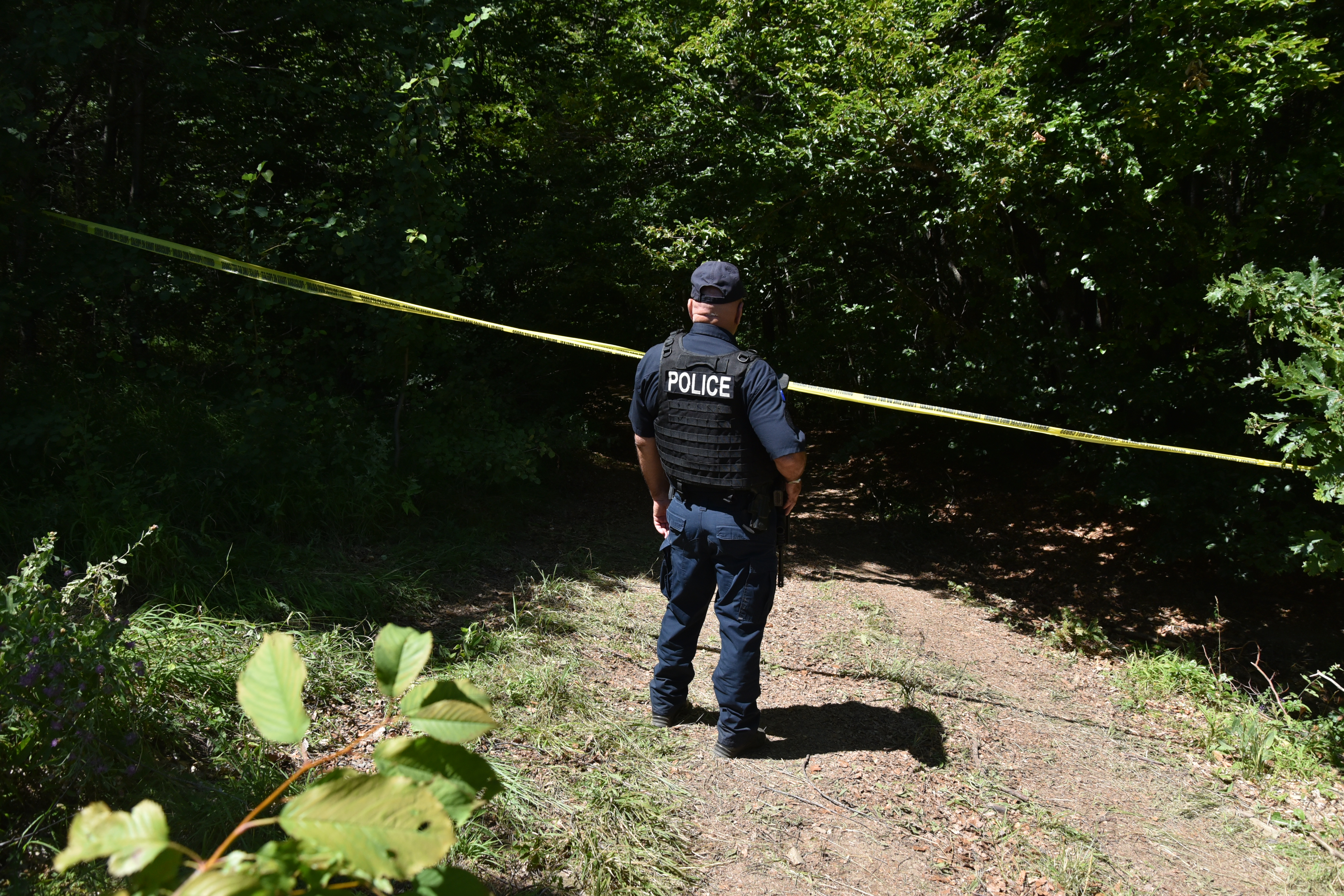Kosovo policeman guards the site where forensic teams have begun excavations of a mass grave near the village of Kalluder, Wednesday, July 29, 2026. (AP Photo/Florent Bajrami)