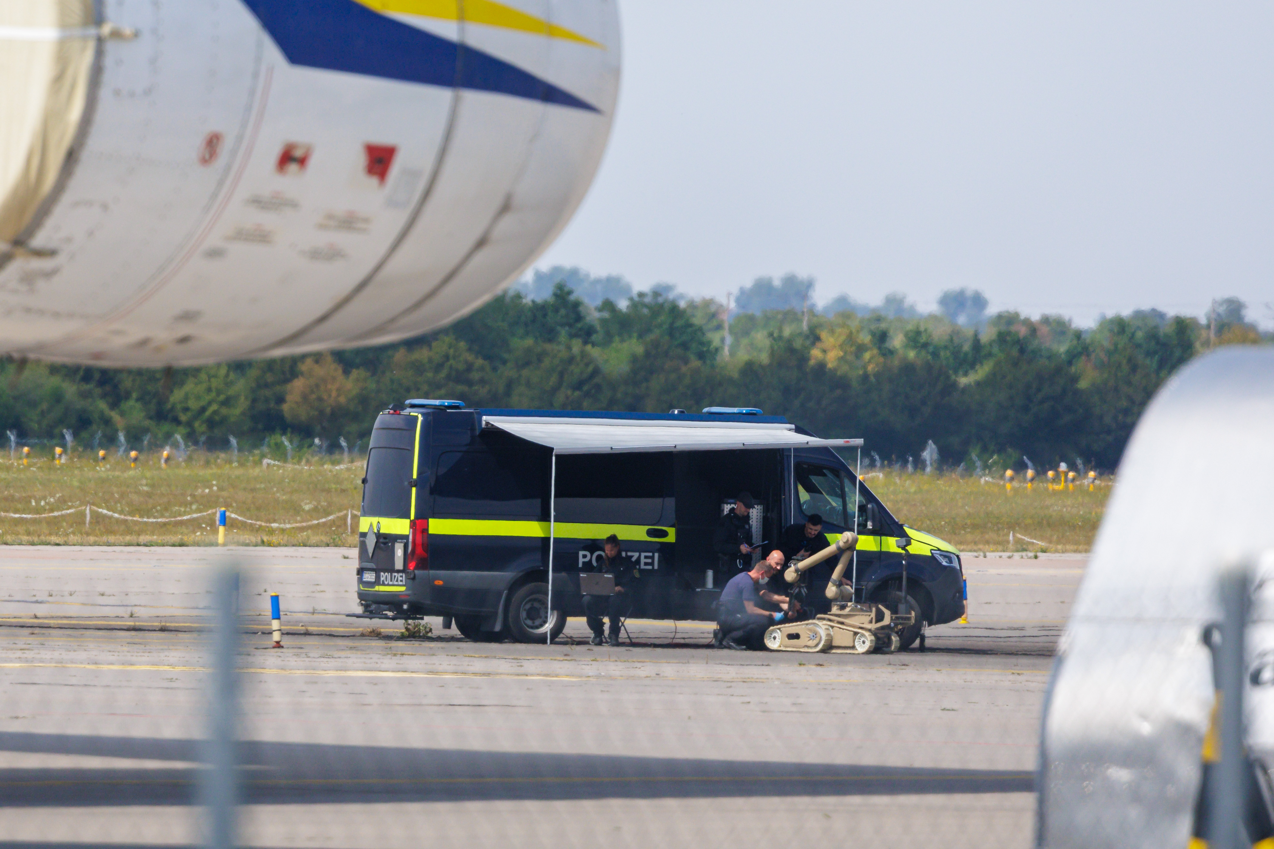 LEIPZIG, GERMANY - AUGUST 5: Police investigators work on the tarmac with a robot that is capable, amongst other things, of defusing explosives, near to Ukrainian Antonov cargo plane at Leipzig/Halle Airport on August 5, 2026 near Leipzig, Germany. Airport workers reportedly discovered a drone yesterday on the tarmac near an Antonov at the airport that was equipped with an explosives detonator and an unidentified substance. Additionally, a DHL cargo plane that took off from the airport late last night collided with a small object, causing minor damage. (Photo by Jens Schlueter/Getty Images)