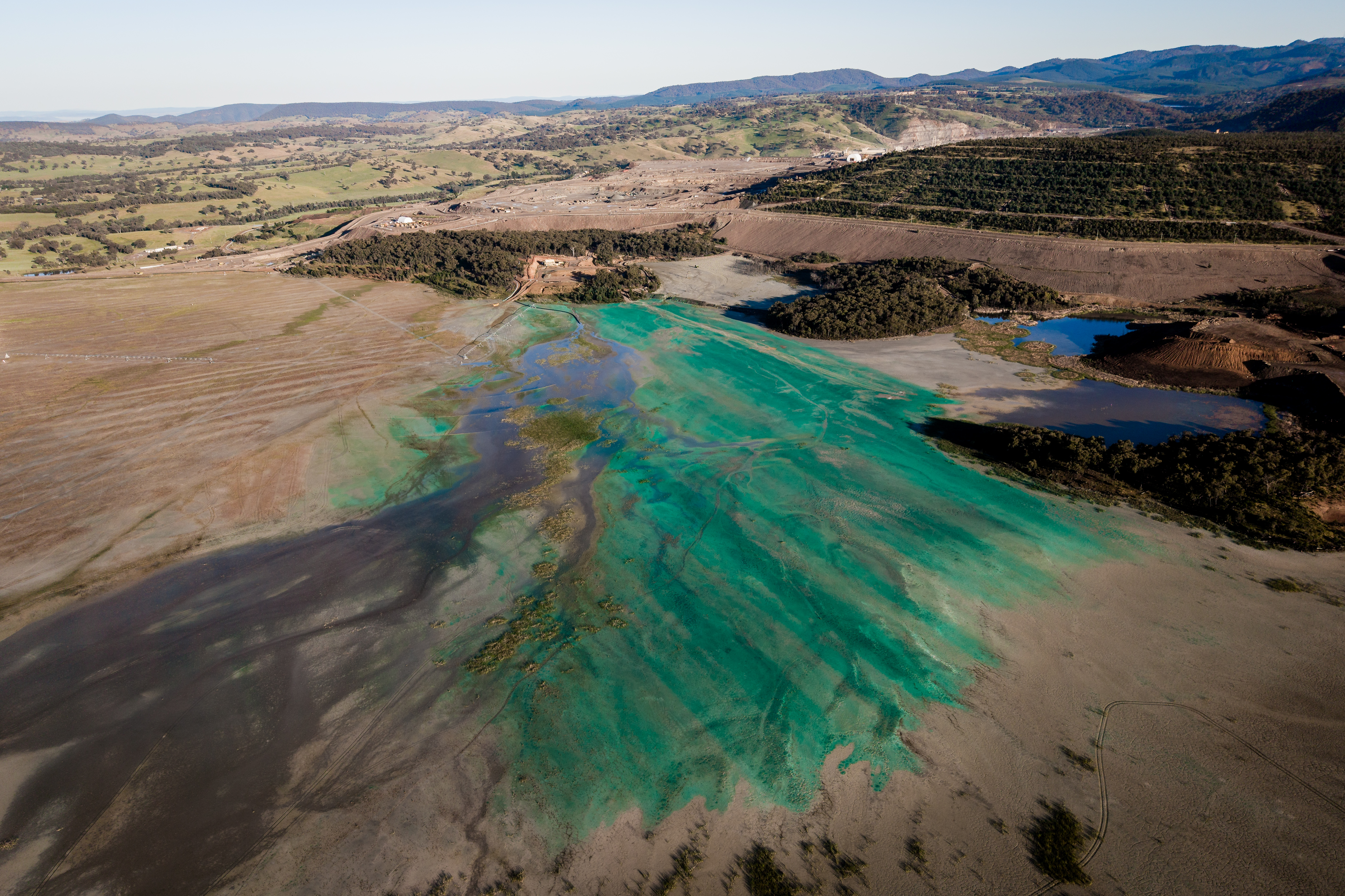 ORANGE, AUSTRALIA - NOVEMBER 08: In an aerial view, a section of a disused tailings dam at the Cadia Goldmine is seen on November 08, 2024 in Orange, Australia. In the central west of New South Wales, Australia, residents near the Cadia gold mine are expressing serious concerns about potential contamination from mining operations. Cadia is the second largest gold mine in Australia. In March 2018 part of the Northern tailings dam wall collapsed, which was one of the largest industrial disasters of its type in Australia. Many community members have reported health issues and elevated levels of heavy metals in their bodies, which they believe stem from dust and water contamination linked to the mine, media reports said. Despite the lack of definitive evidence connecting the mine to health problems, local residents are advocating for better regulatory oversight and transparency regarding environmental impacts. Newmont Corporation, the mine's owner, has recently filed a submission to continue mining at Cadia until at least 2050, a move the mining giant says will expand the gold mine's footprint in the area. Residents have raised concerns about the current and future potential impacts of the mine on the nearby Belubula River, which is home to significant populations of Platypus and Murray Cod. As tensions rise, the community grapples with the balance between economic benefits from mining and the urgent need to protect public health and the environment – a dynamic that may play out around other mines as demand for raw materials soars. (Photo by Brook Mitchell/Getty Images)