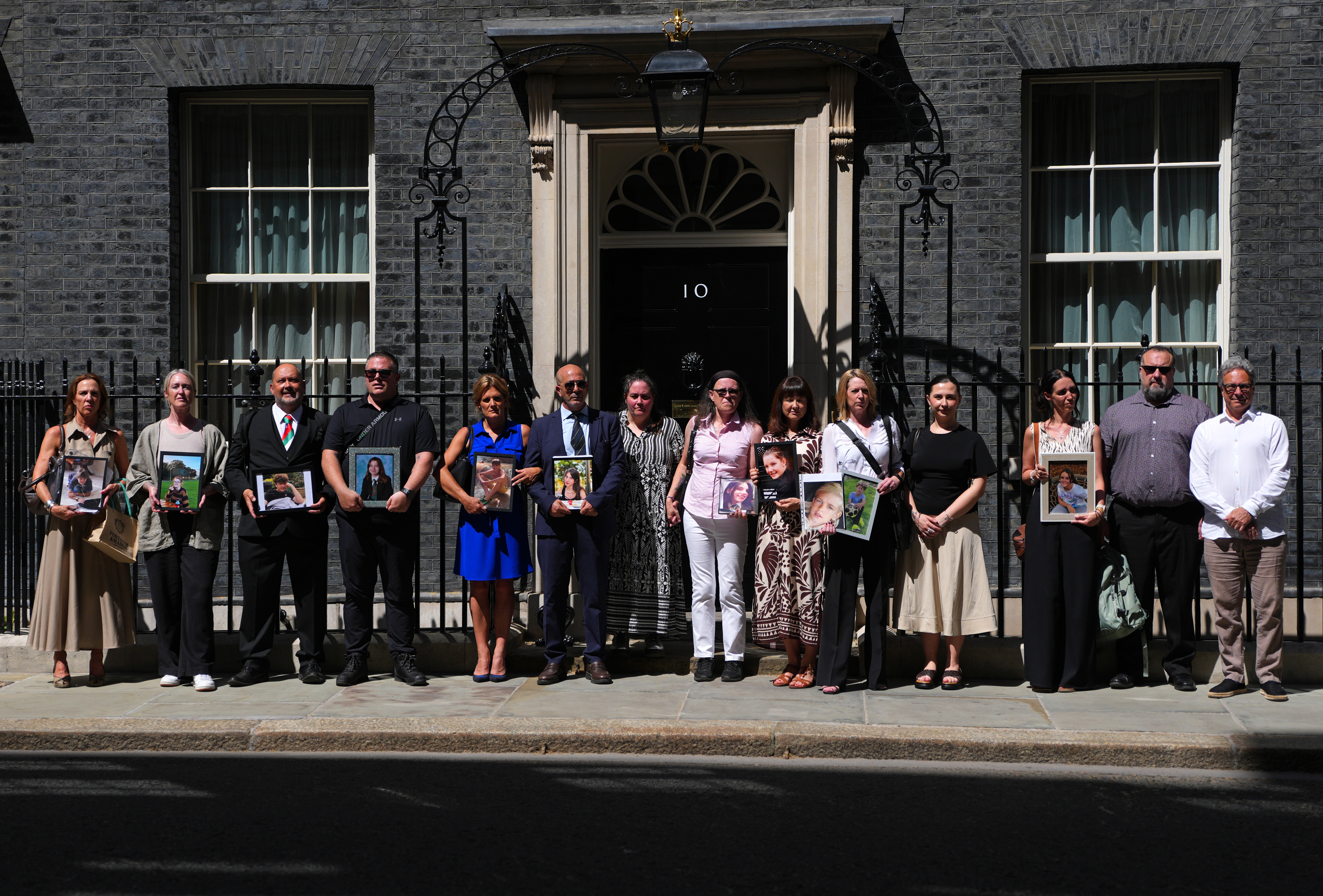 LONDON, ENGLAND - MAY 26: Bereaved parents pose with images of their children outside Downing Street on May 26, 2026 in London, England. Keir Starmer is holding a round table with bereaved parents to discuss how tech giants should provide safe products, and how just a ban on social media for the under-16s would let the companies "off the hook". (Photo by Carl Court/Getty Images)