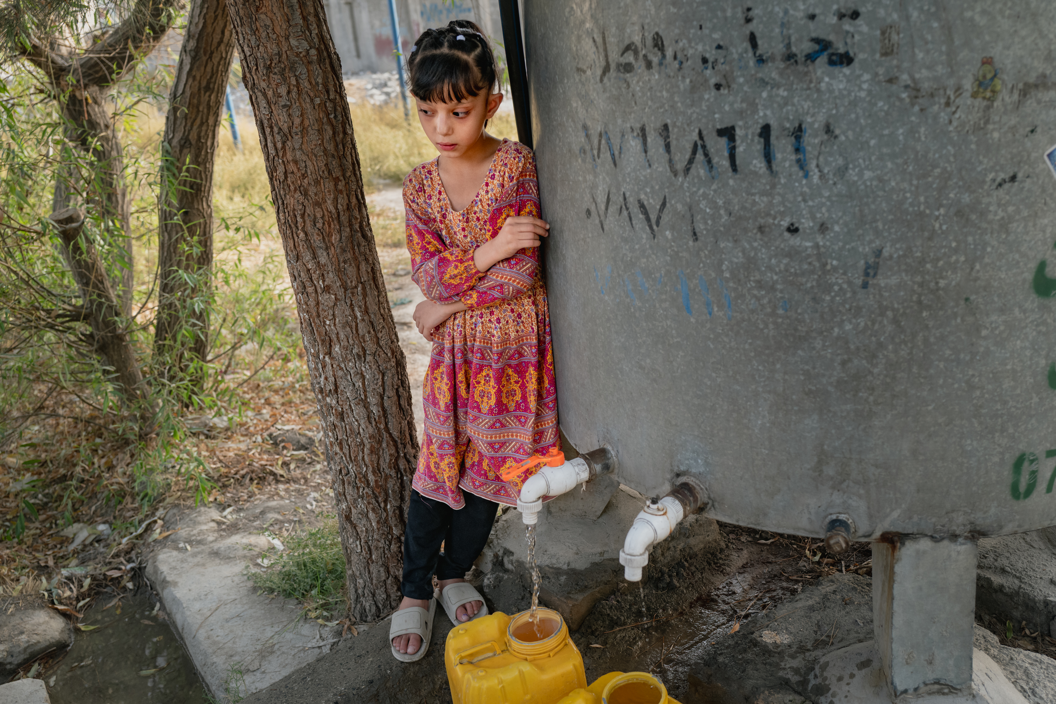 A girl fills canisters of water from a tap.