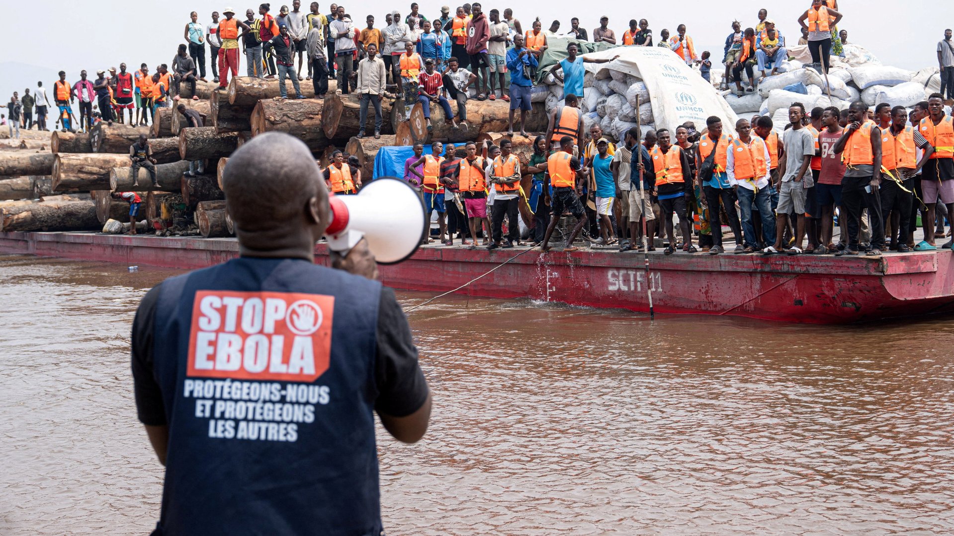 A volunteer uses a megaphone to make announcements while intercepting a passenger boat, after, according to officials, a passenger who had disembarked earlier died after developing symptoms consistent with Ebola, in a place given as Kinshasa, Democratic Republic of the Congo, in this handout image released on August 5, 2026. [International Organization For Migration/Handout]