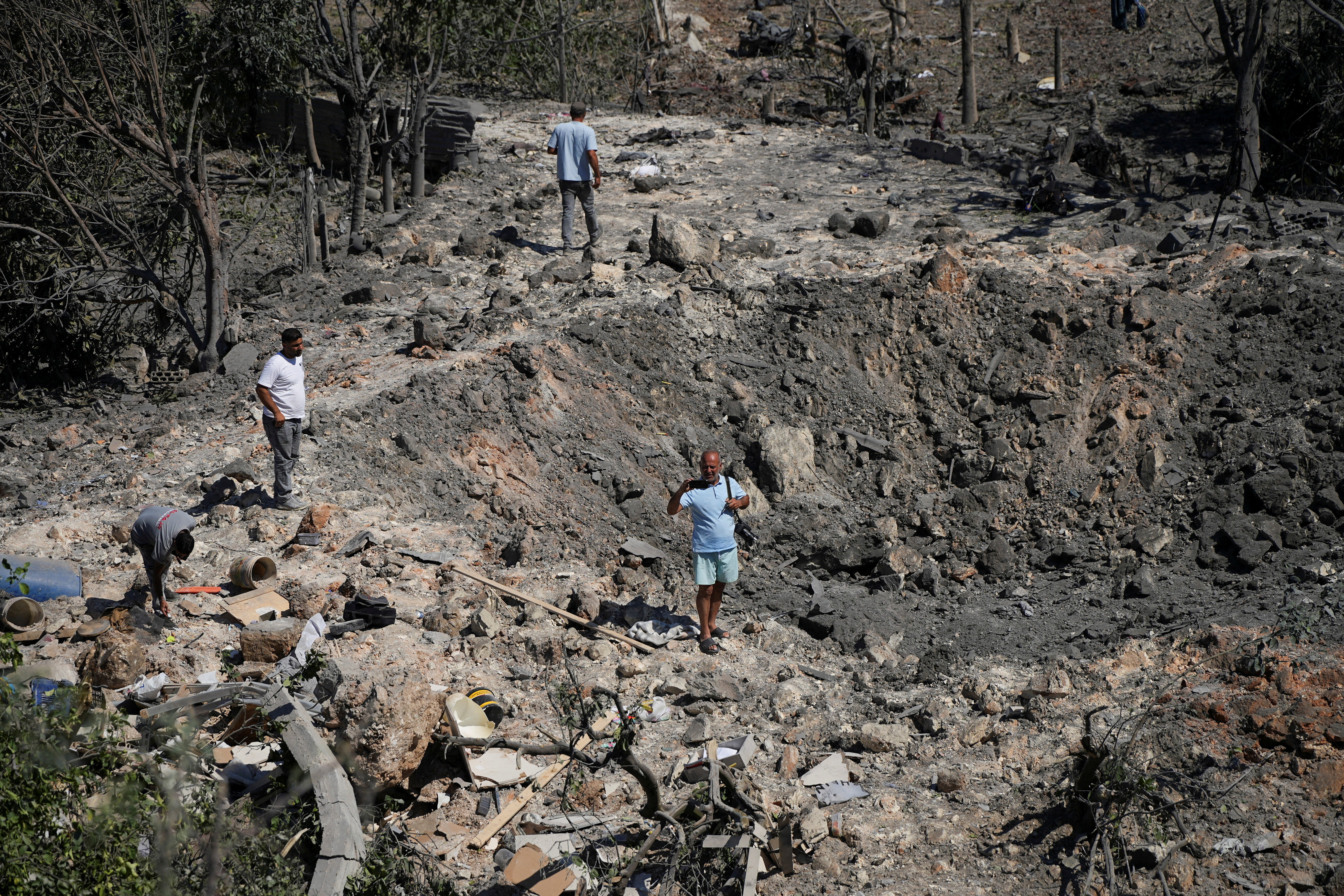 People and journalists stand at a site hit by Israeli strikes that occurred in the early hours of Thursday, according to Lebanon’s state news agency NNA, in Burj al-Shamali, southern Lebanon, August 6, 2026. REUTERS/Stringer TPX IMAGES OF THE DAY
