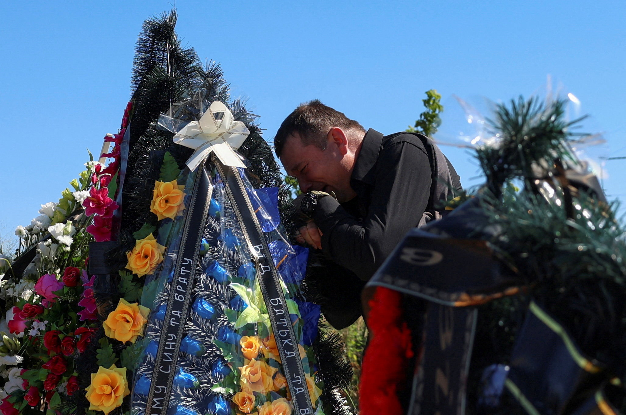 Petro Ionov reacts near a grave of his son Yevhenii Ionov after a burial ceremony on a cemetery in the town of Bilohorodka, amid Russia's attack on Ukraine, in Kyiv region, Ukraine August 25, 2026. Yevhenii Ionov was among at least seventeen people killed by Russian missile and drone strikes towards Kyiv on August 20, according to mayor Vitali Klitschko. Civilian casualties from Russia's full-scale invasion rose sharply in July as missiles and drones struck cities far from the front lines, the United Nations said in a report published on August 14. The U.N. Human Rights Monitoring Mission in Ukraine said it had confirmed at least 437 civilians killed and 2,610 injured during the month, a 30% increase from June and the highest toll since May 2022.REUTERS/Anatolii Stepanov TPX IMAGES OF THE DAY