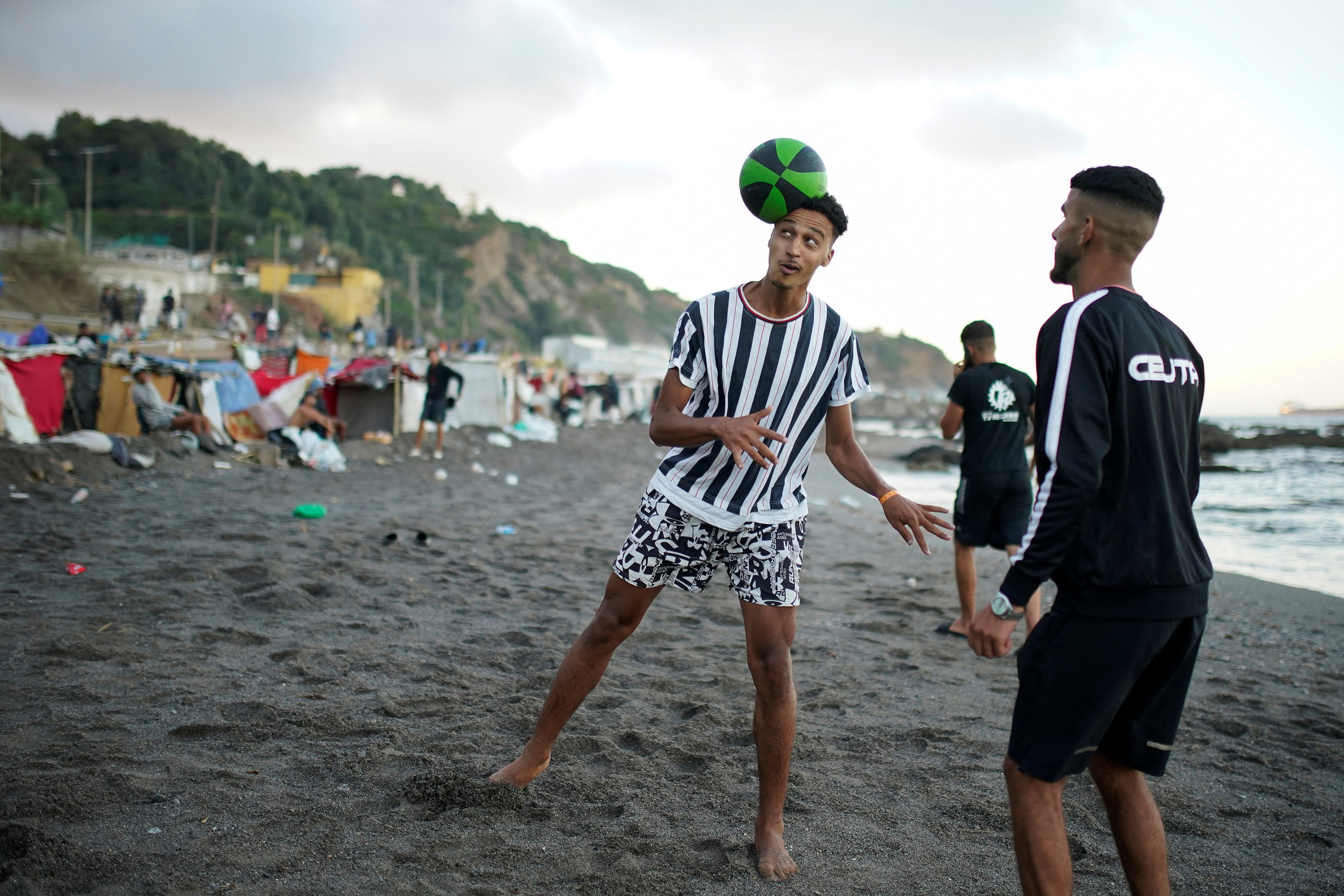 Amine Hoummad, 28, plays football at a settlement in Trampolin Beach, following mass crossings of migrants from Morocco in Ceuta, Spain, September 11, 2026. REUTERS/Ana Beltran