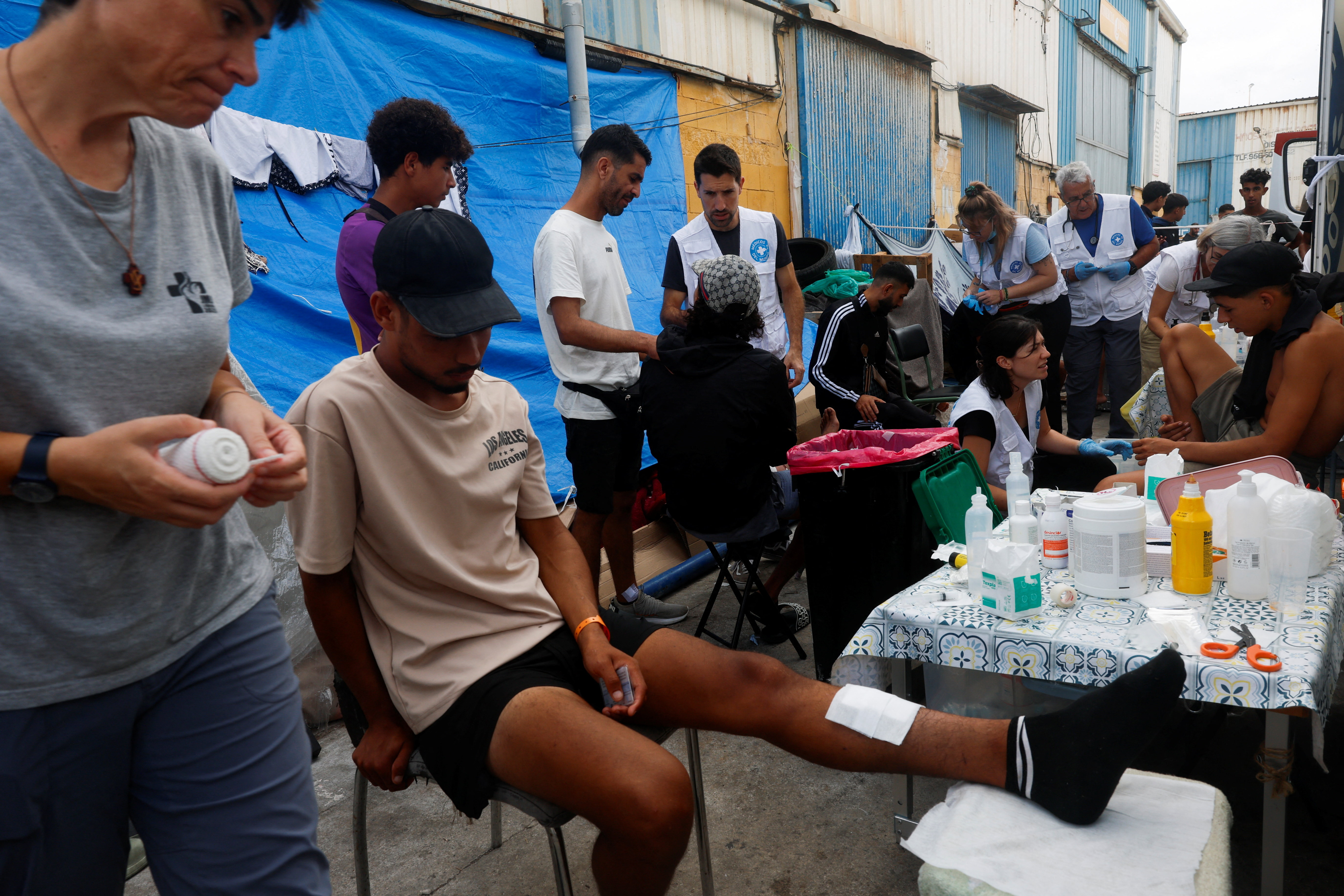 Members of a Spanish NGO Medicos del Mundo (Doctors of the World) help injured migrants at an industrial area, following the mass crossing of migrants from Morocco, in Ceuta, Spain, September 21, 2026. REUTERS/Jon Nazca