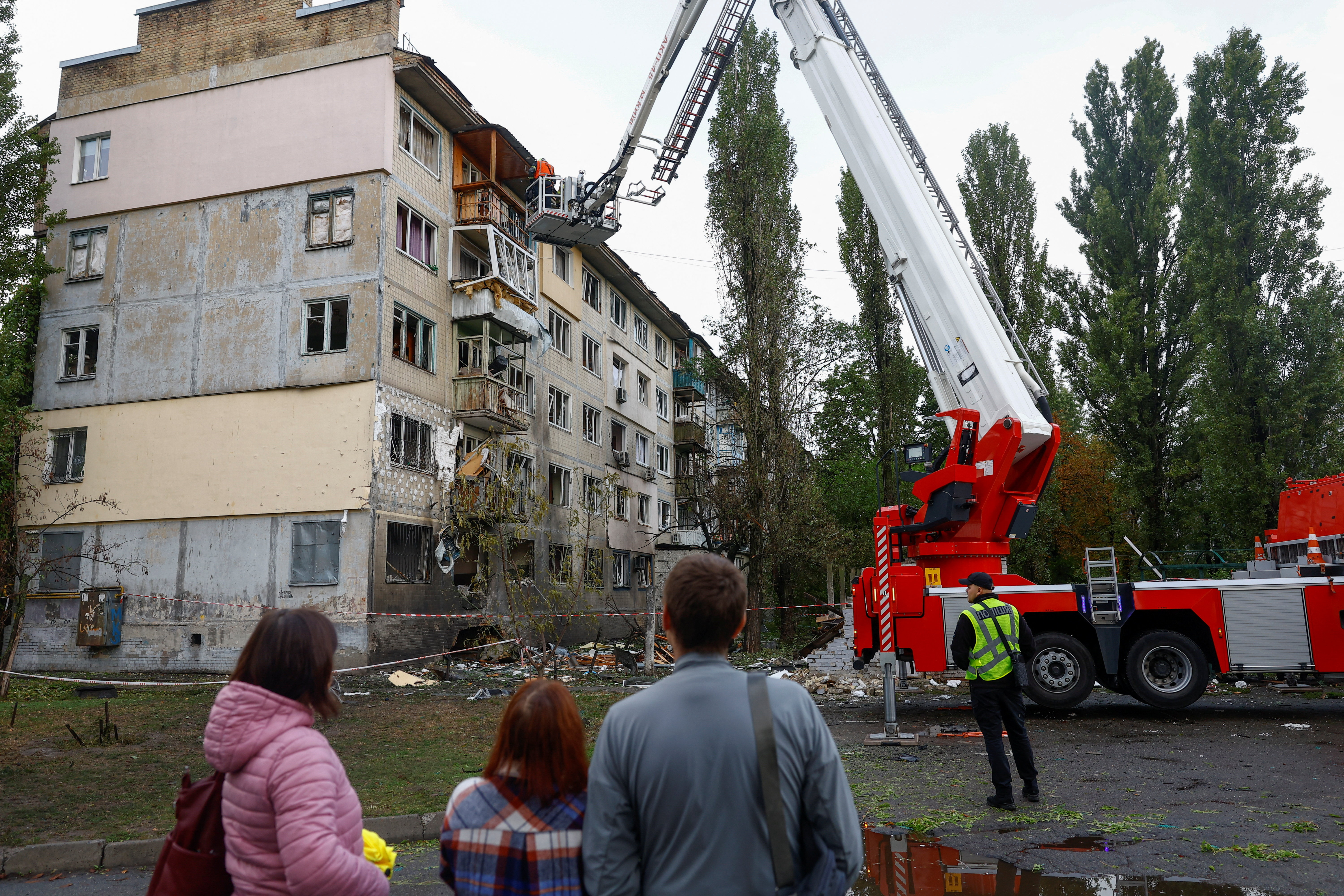 Residents look at an apartment building, hit by a Russian drone in Kyiv, Ukraine