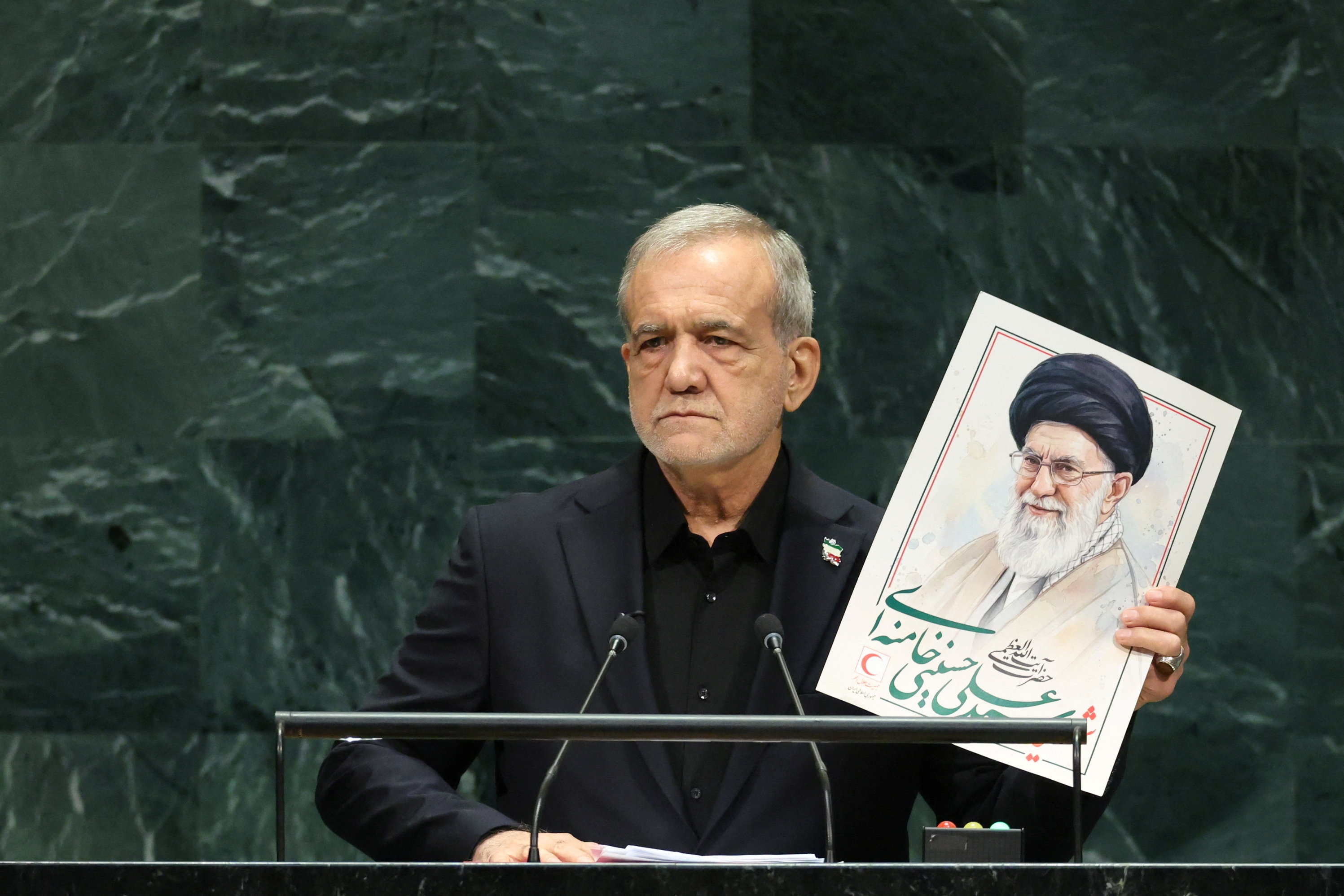 Iran’s President Masoud Pezeshkian holds up a picture of former Supreme Leader Ayatollah Ali Khamenei, who was assassinated in a US-Israeli attack in February, as he addresses the United Nations General Assembly on Wednesday