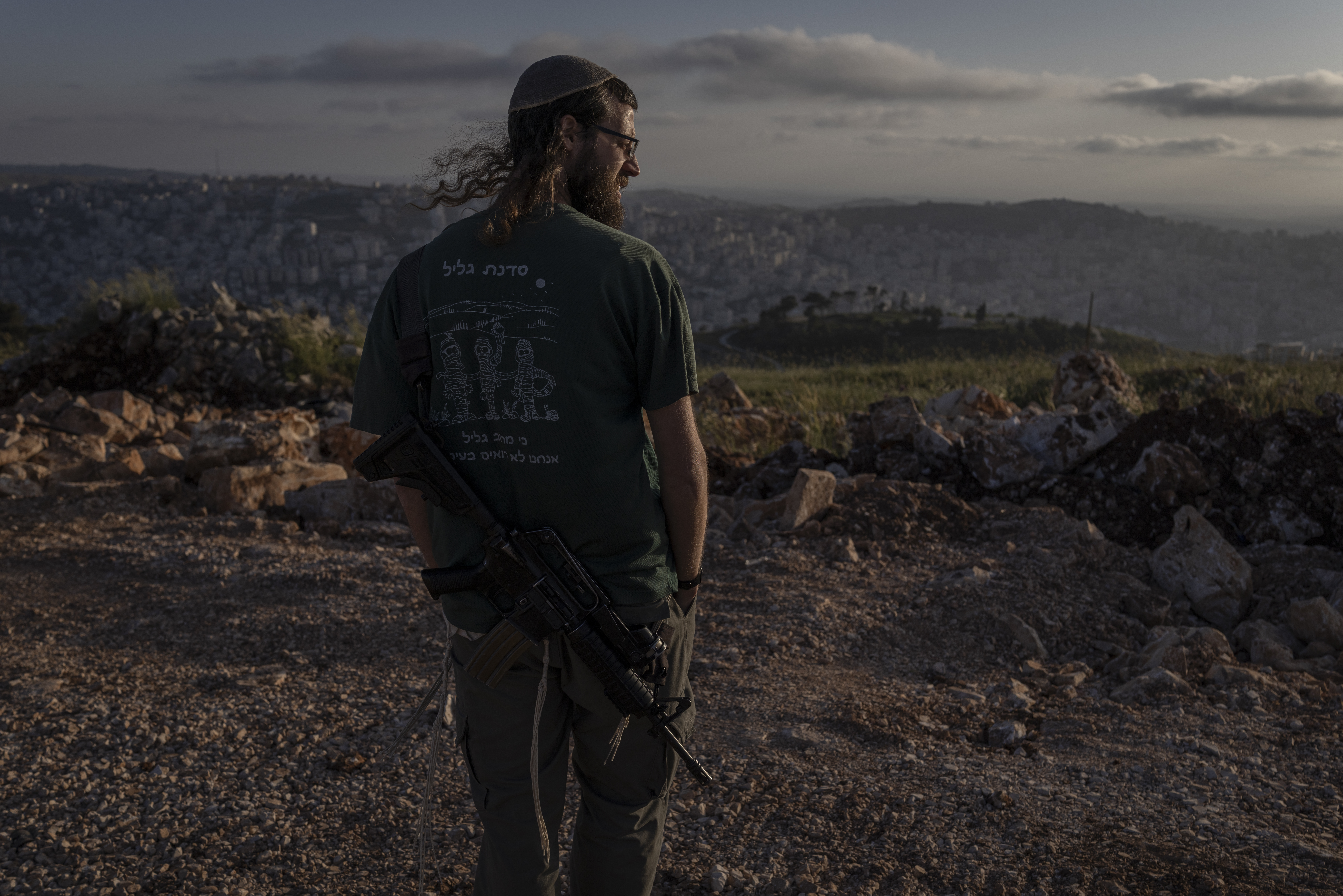An armed Israeli settler stands overlooking Nablus from Har Ebal (Mount Ebal) settlement in the Israeli-occupied West Bank, on April 28, 2026. Israeli ministers on April 19 officially reopened Sa-Nur, a settlement in the occupied West Bank that was evacuated 20 years ago, marking the occasion with defiant declarations against Palestinian statehood and calls to resettle Gaza. (Photo by ilia YEFIMOVICH / AFP)