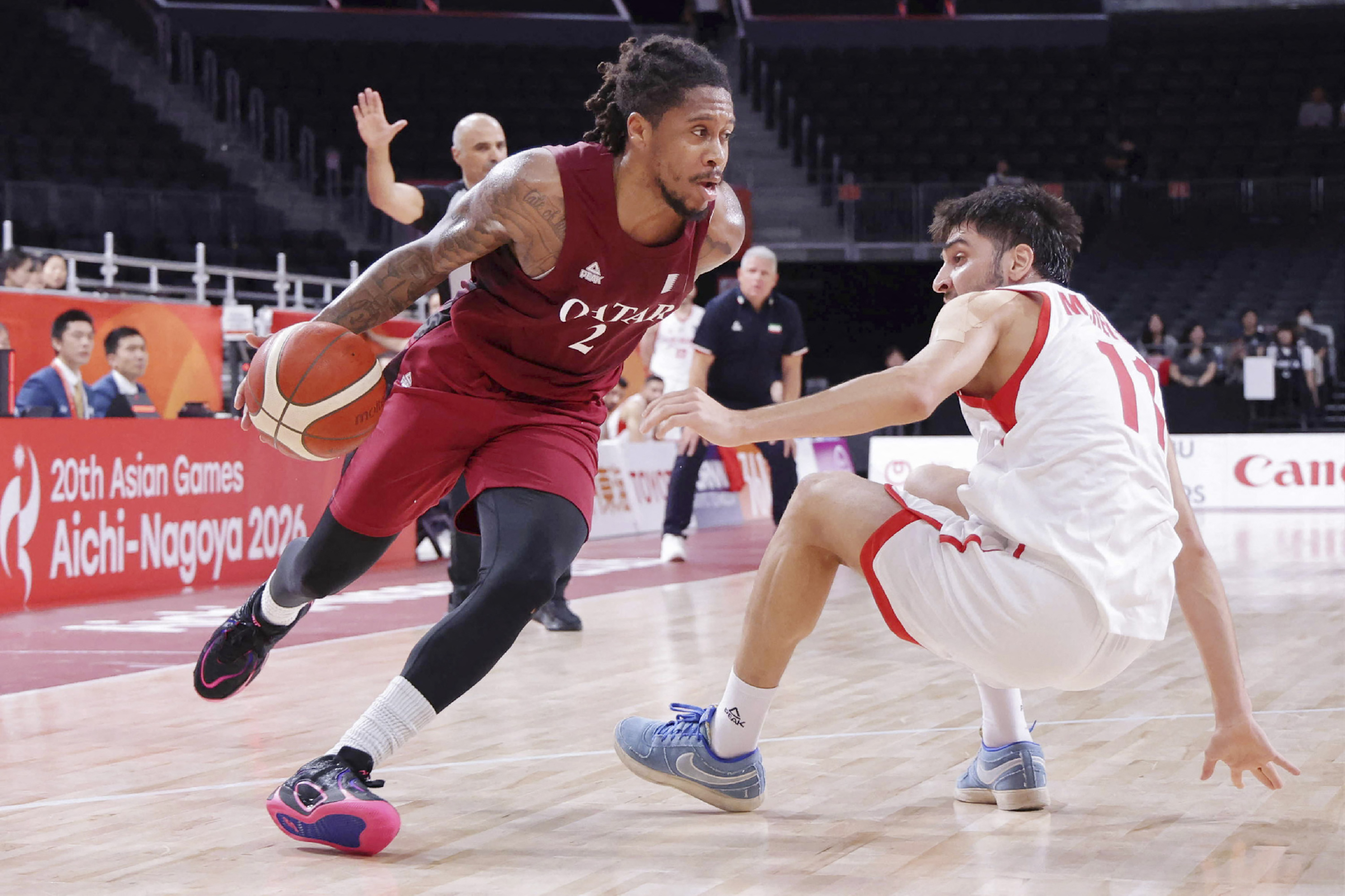 Qatar's Mike Lewis II (L) dribbles past an opponent in a game.