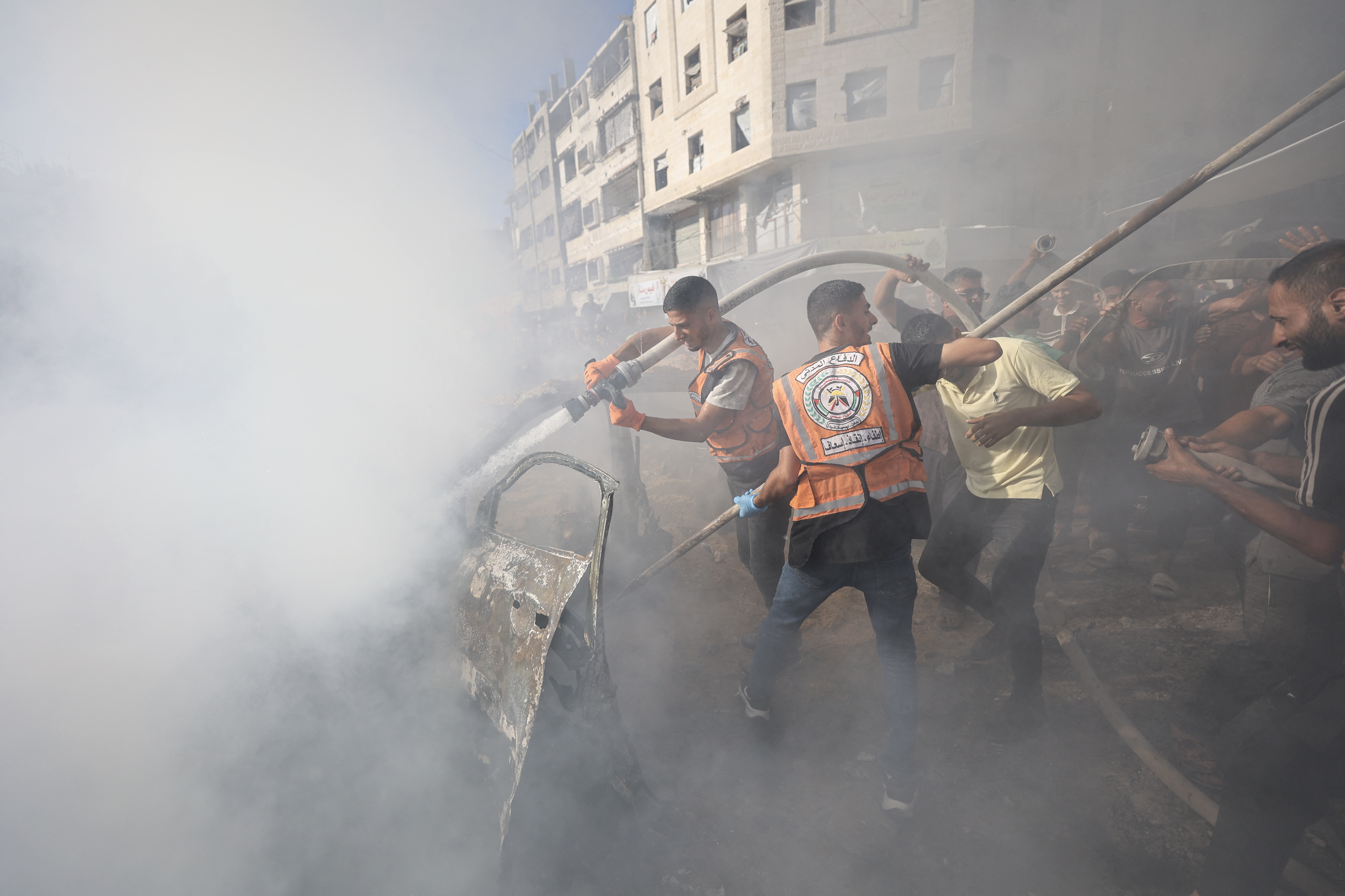 Palestinian emergency personnel attempt to extinguish a burning vehicle