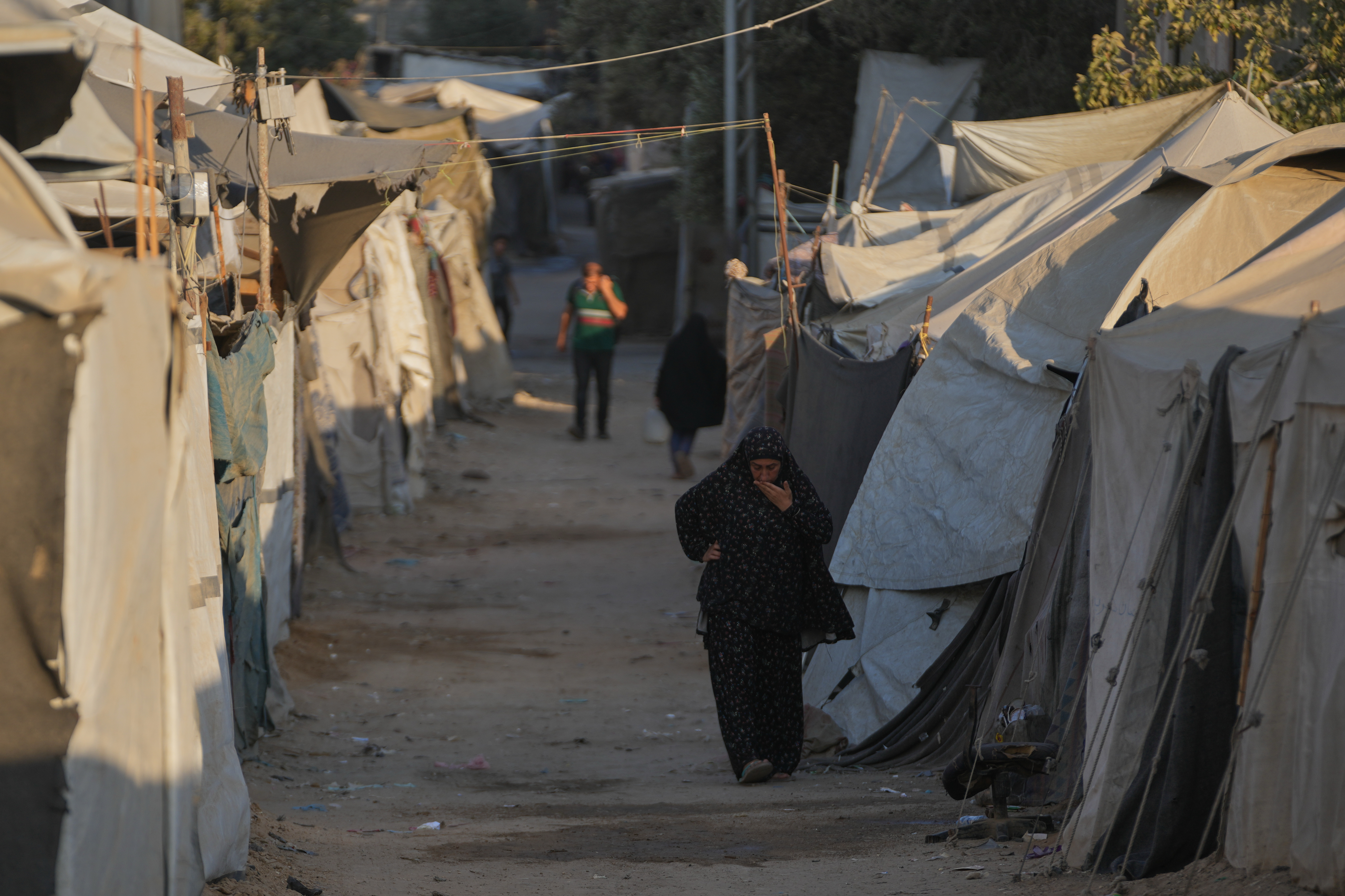 A Palestinian woman walks along tents at a makeshift camp for displaced people in Deir al-Balah, central Gaza Strip, on Aug. 6, 2026 [Abdel Kareem Hana/AP]