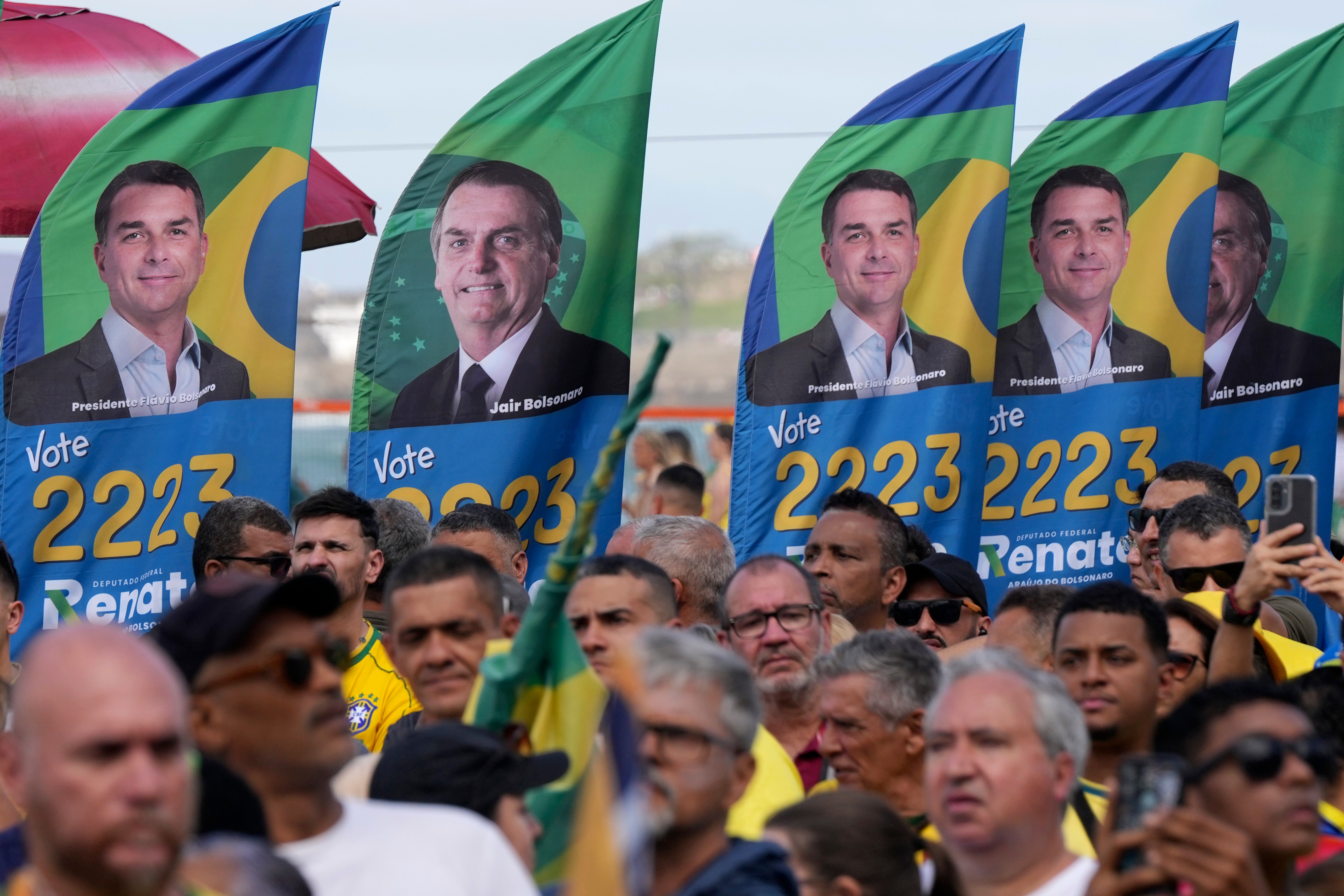 Campaign posters showing opposition presidential candidate Flavio Bolsonaro and his father, former President Jair Bolsonaro, are displayed by supporters during Flavio's campaign rally in Rio de Janeiro, Brazil, Sunday, Aug. 16, 2026. (AP Photo/Silvia Izquierdo)