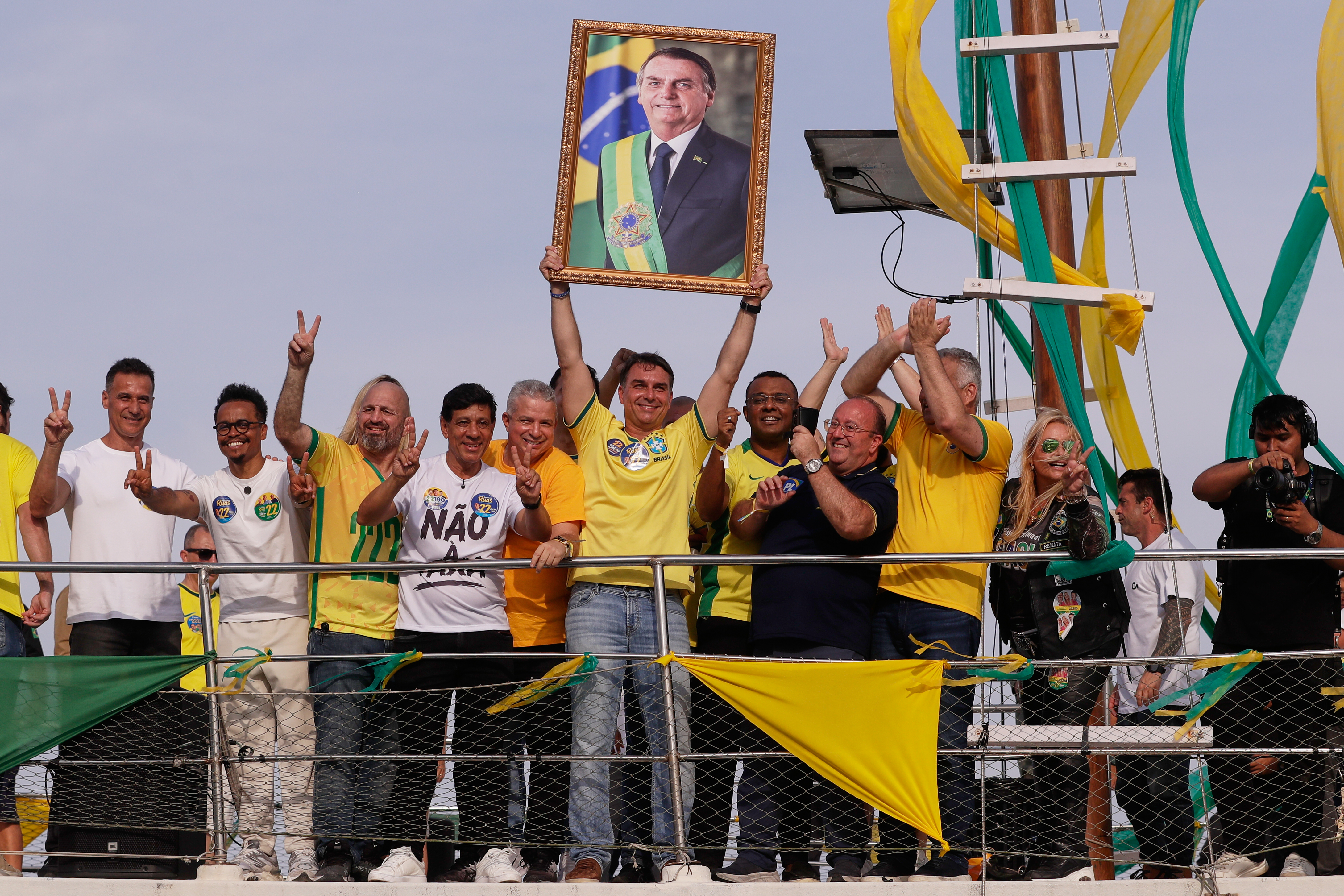 Opposition presidential candidate Flavio Bolsonaro holds a photo of his father, former President Jair Bolsonaro, as he rides a boat during a campaign rally ahead of the October general elections in Angra dos Reis, Rio de Janeiro state, Brazil, Saturday, Aug. 29, 2026. (AP Photo/Bruna Prado)