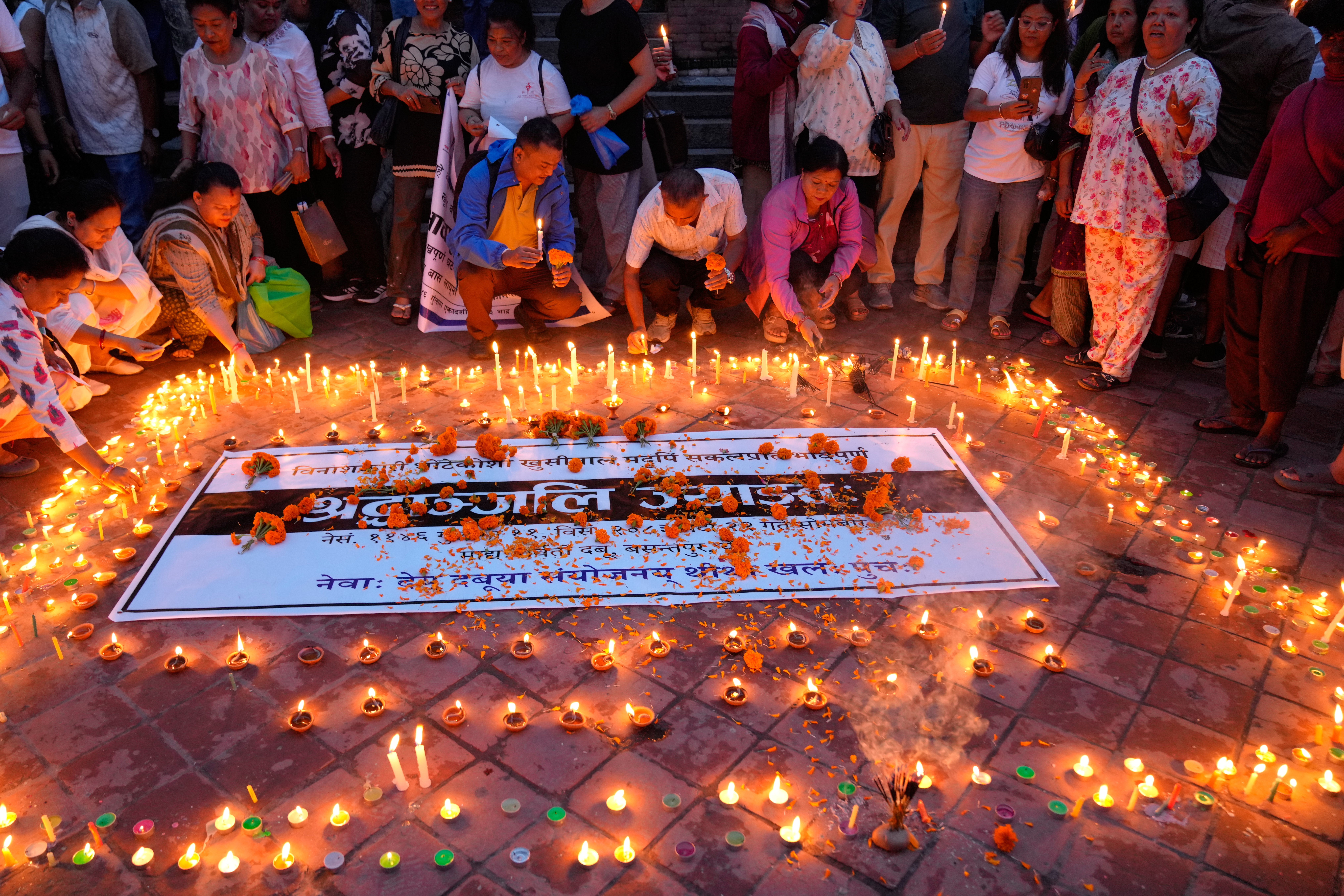 People light candles and pray during a day of mourning for those killed in the August 26 floods in Kathmandu, Nepal, Monday, September 7, 2026