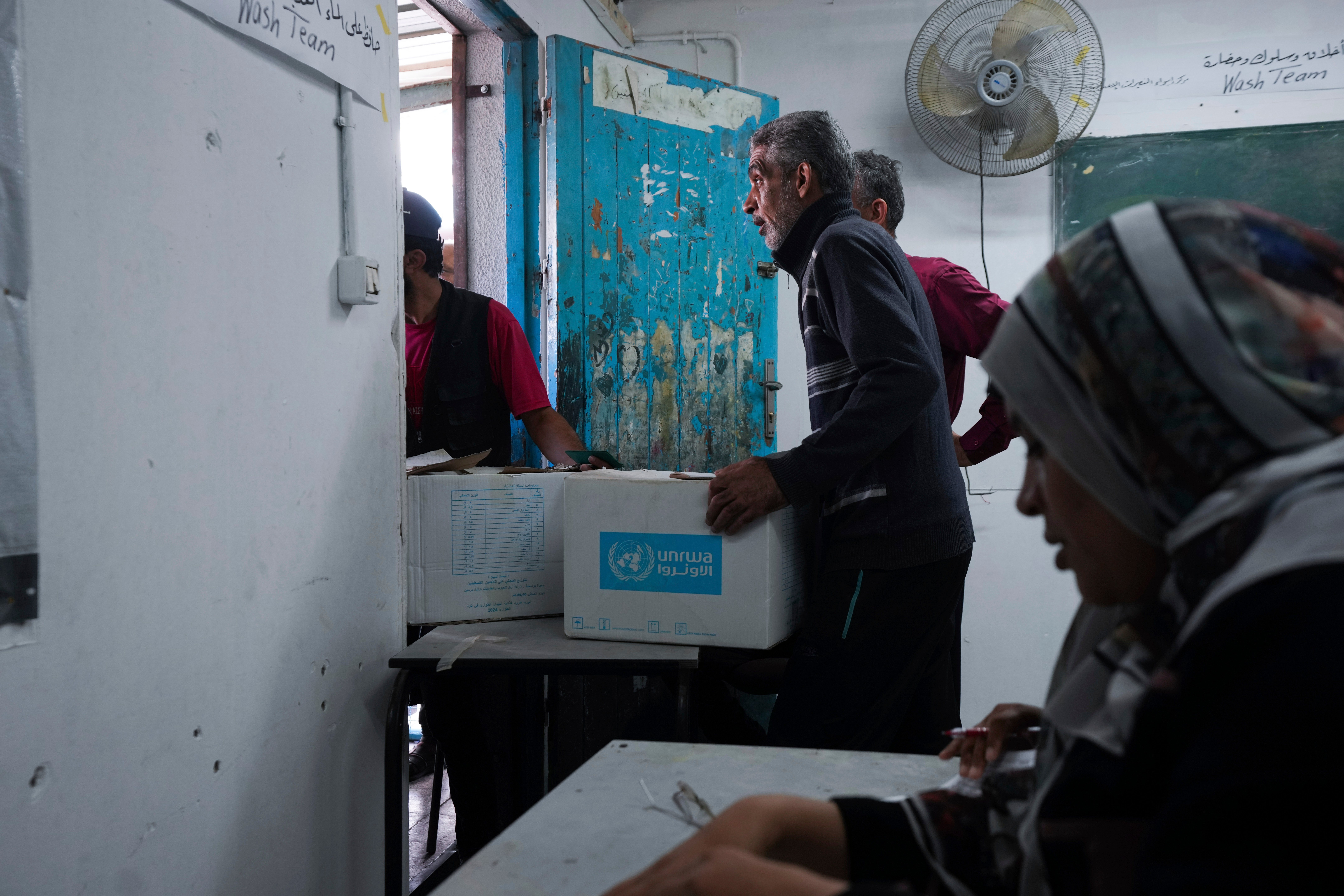 Palestinians receive aid distributed by UNRWA, in the Nuseirat refugee camp, Gaza