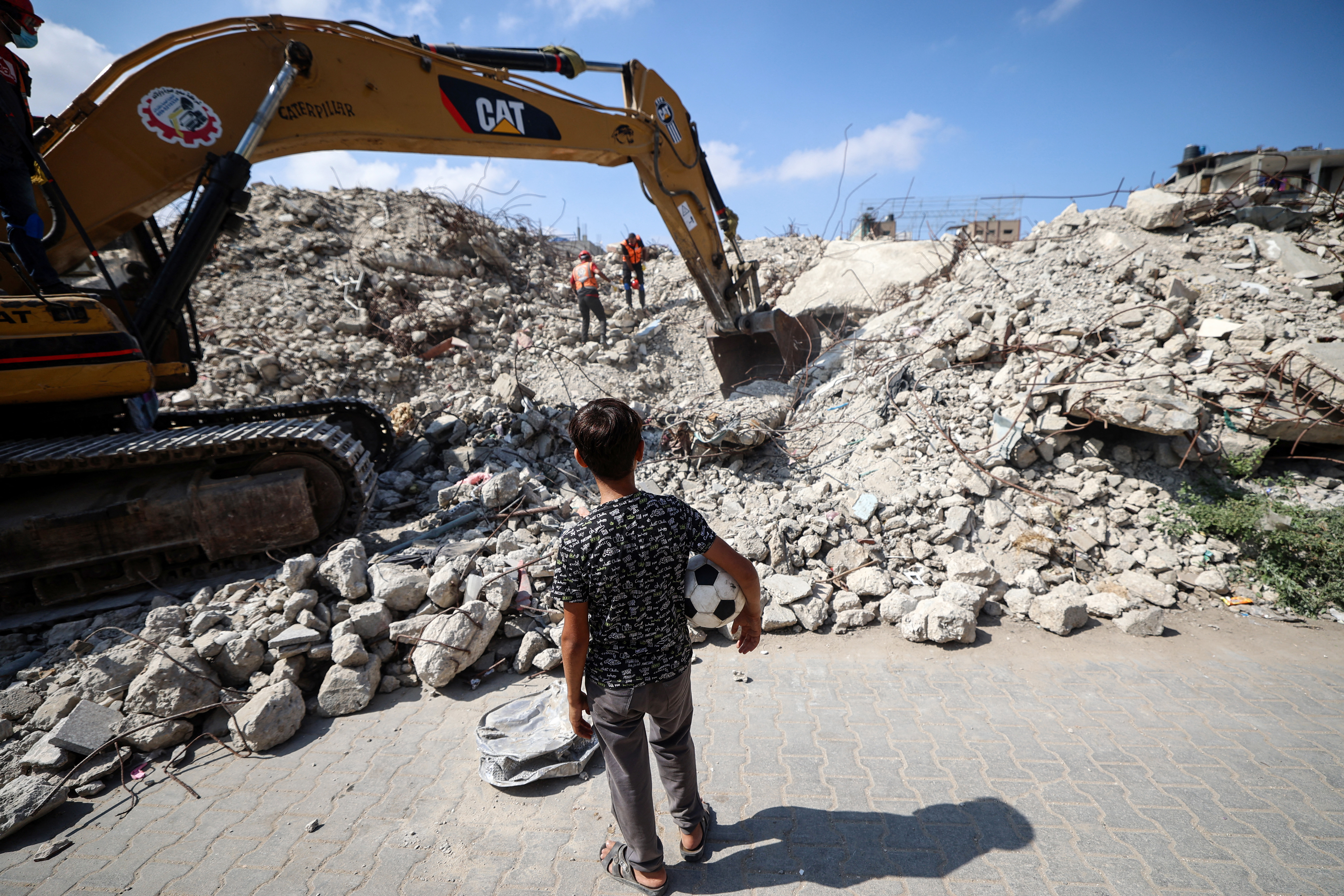 A young boy looks on as civil defence personnel dig through the rubble.