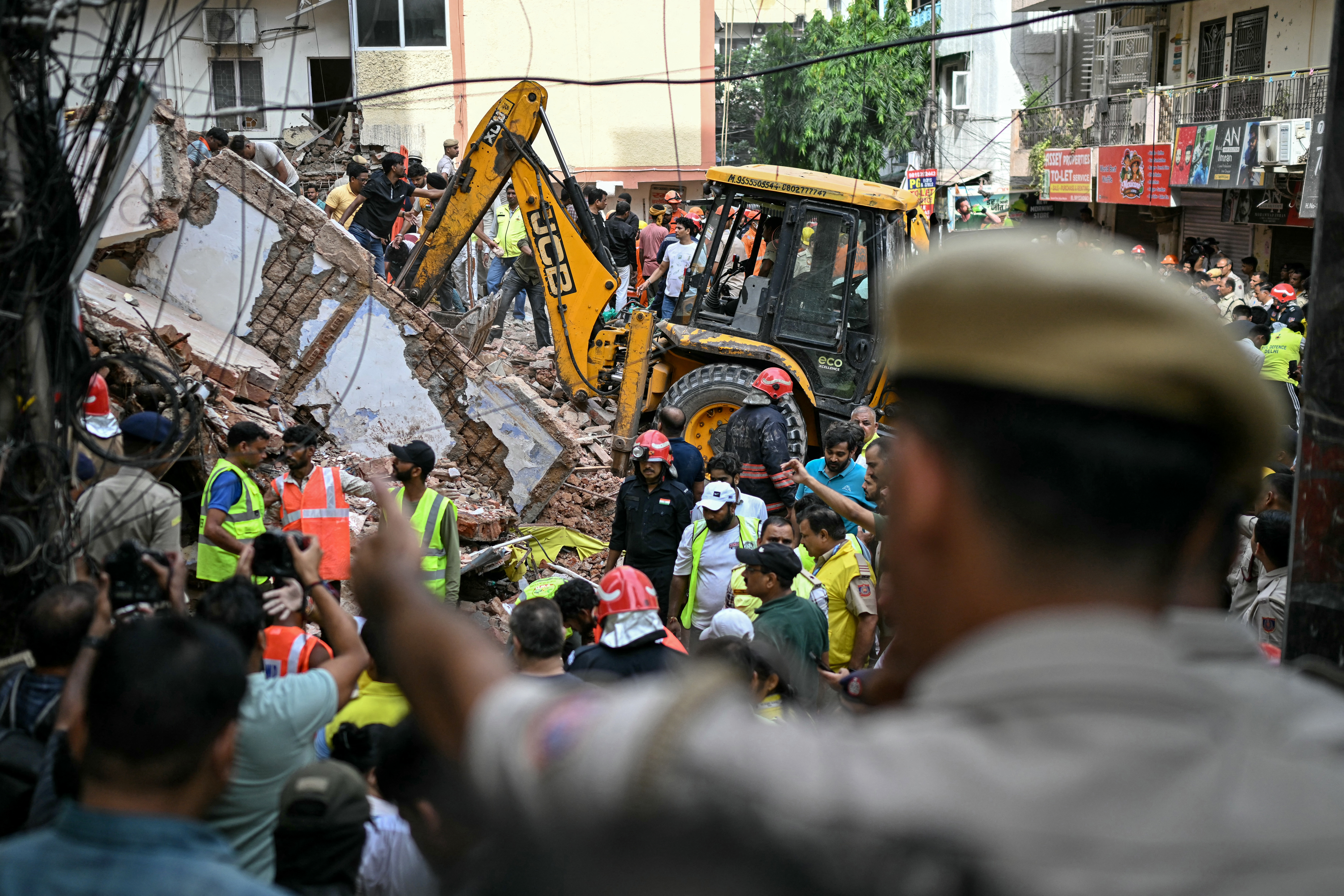 Security personnel stand guard as rescue personnel conduct a search operation at the site following a building collapse in the Satya Niketan area in New Delhi on September 6, 2026. [AFP]