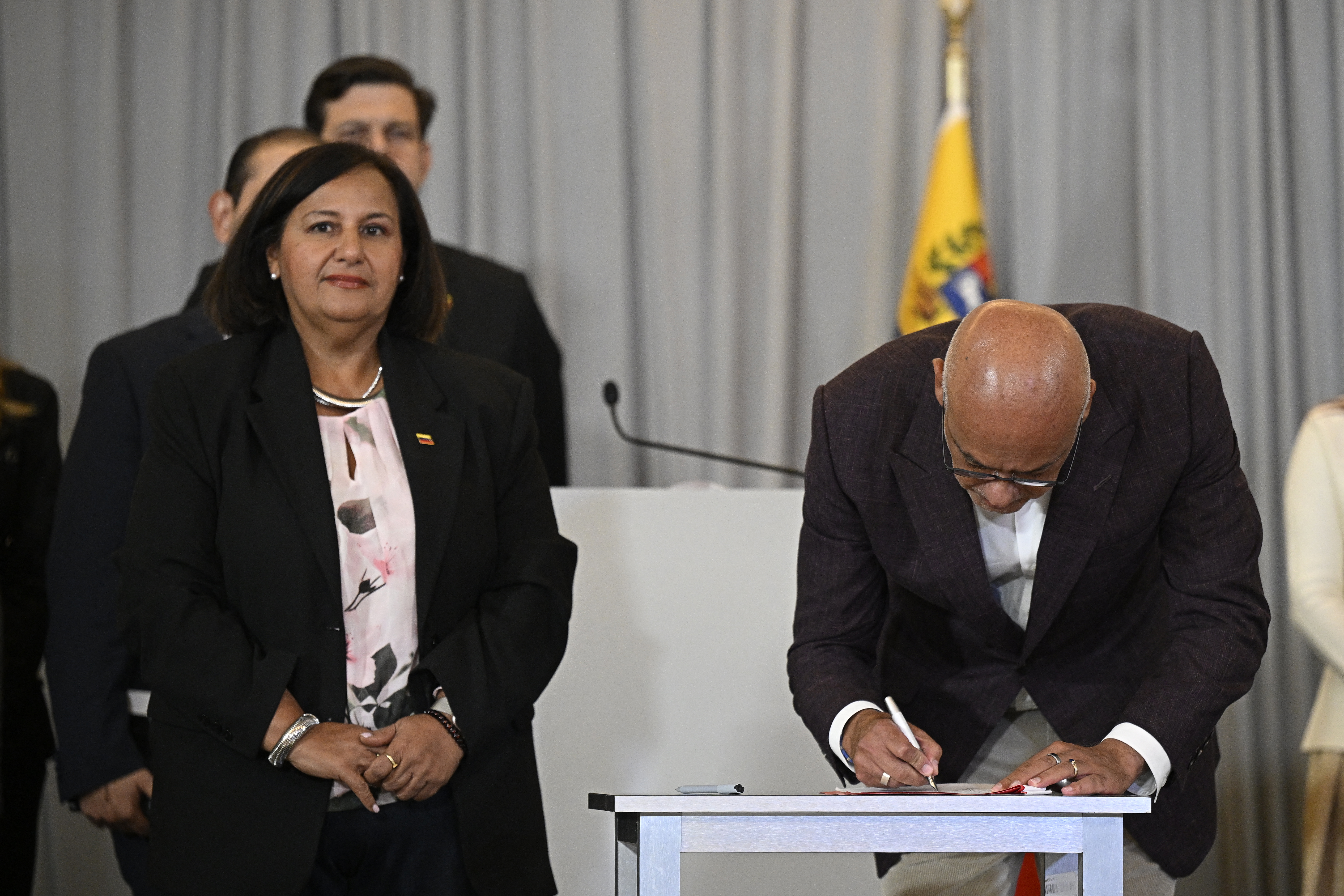 Venezuela's National Assembly President Jorge Rodriguez signs an agreement as opposition delegation head Dinorah Figuera stands beside him at the closing of the second round of political dialogue talks at the Melia hotel in Caracas on September 25, 2026.