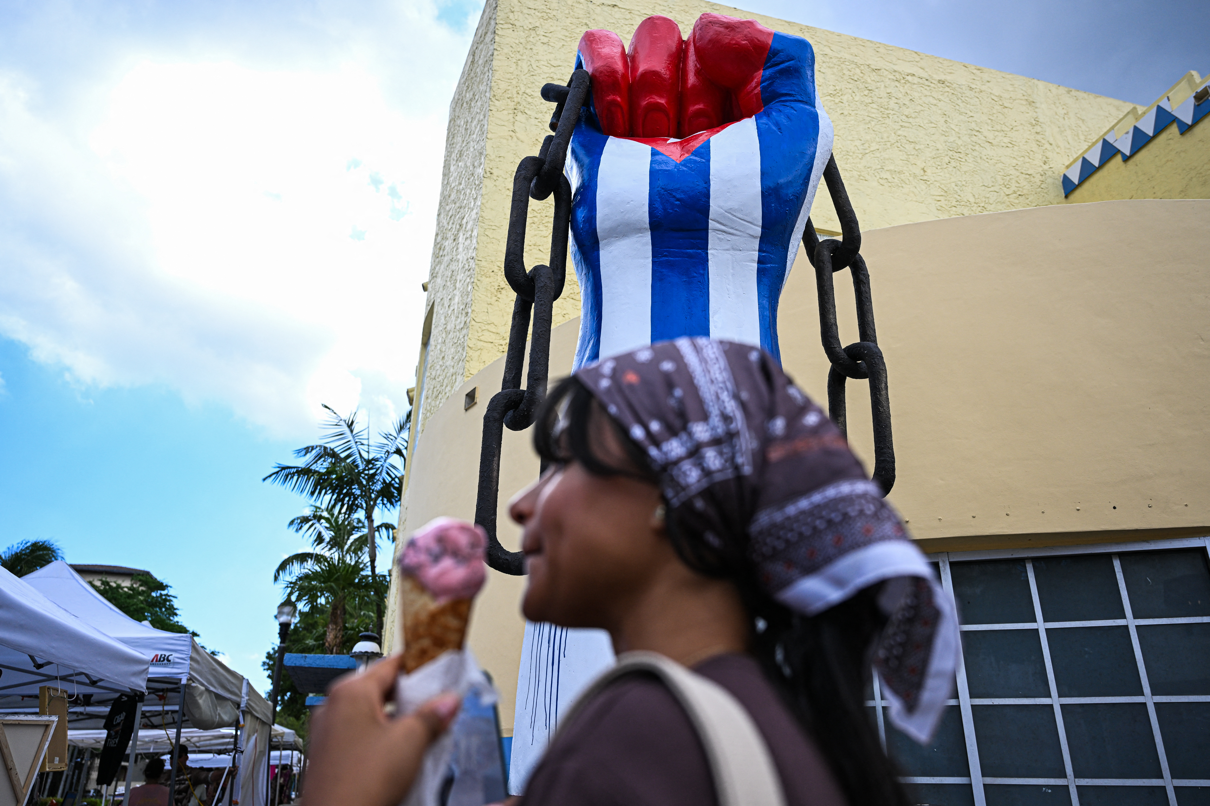 A person passes a sculpture of a raised fist painted in the colors of the Cuban flag by Cuban-born artist Julio Cesar stands the Little Havana neighborhood in Miami, Florida, on September 25, 2026.