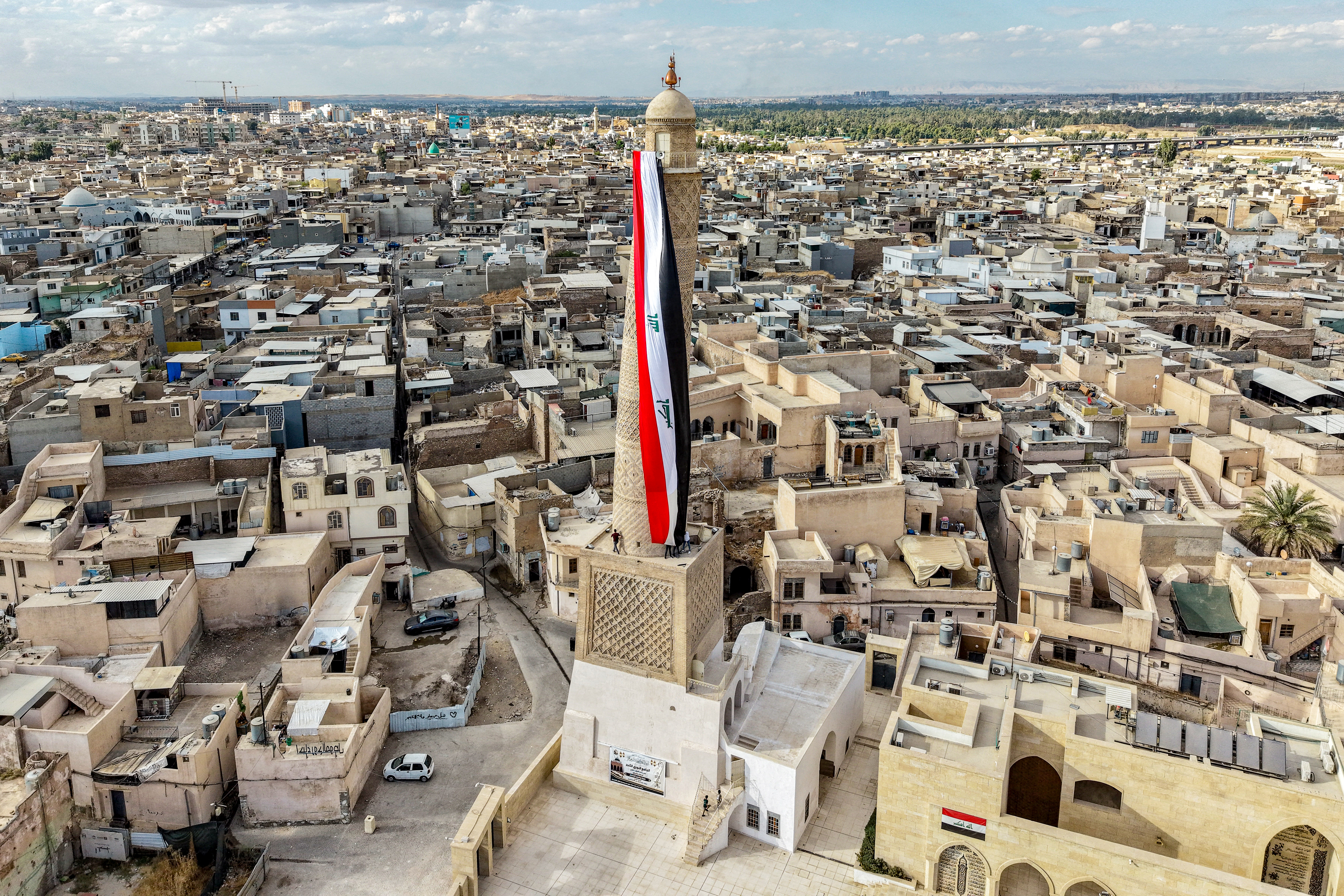 A giant Iraqi flag hangs off the reconstructed 12th century "Hadba" leaning minaret at the historic Great Mosque of al-Nuri in the old city of Mosul on September 29, 2026 as Iraq marks the withdrawal of the US-led anti-Islamic State coalition forces from the country.