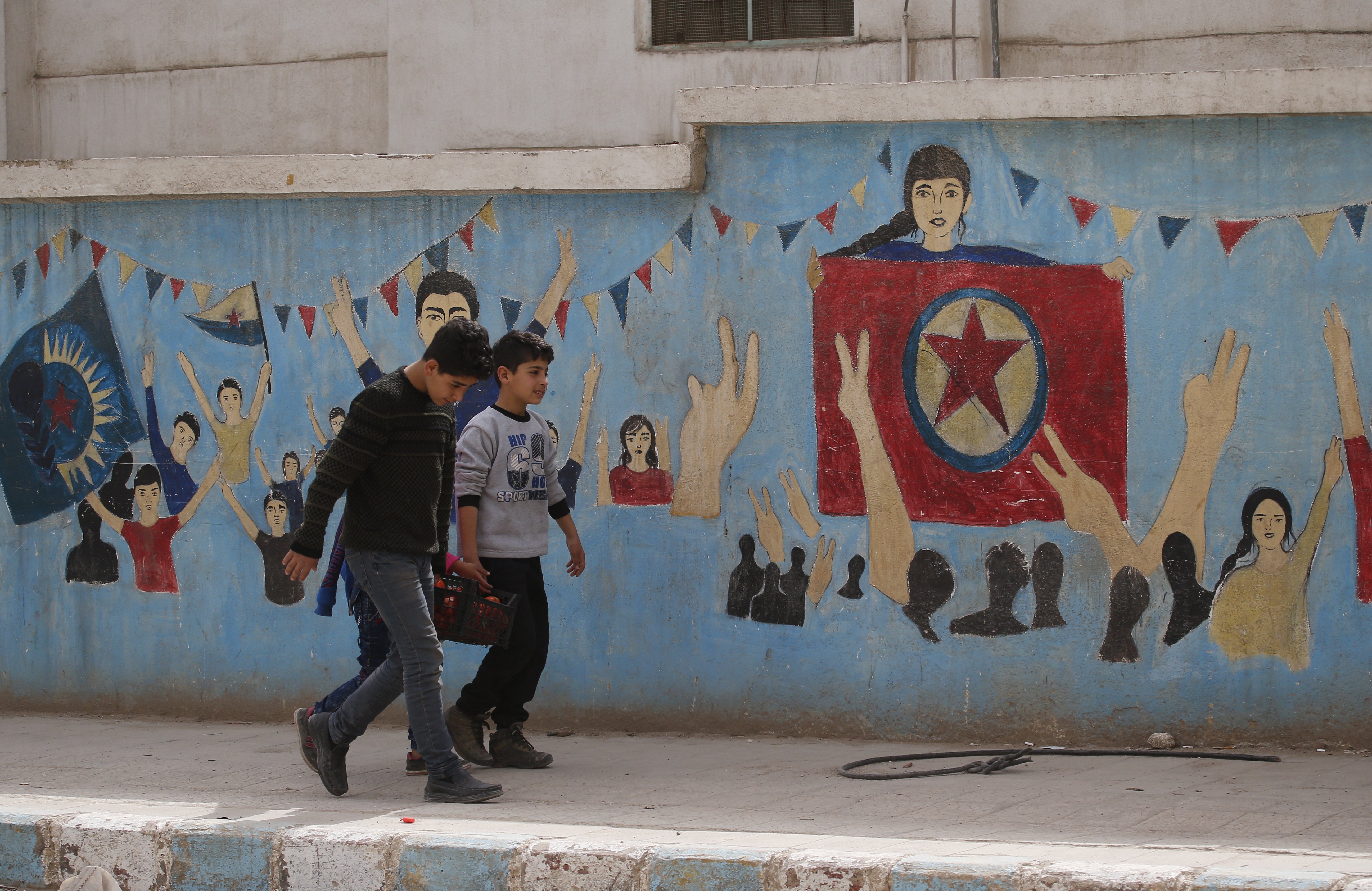Children carrying food walk in a street.