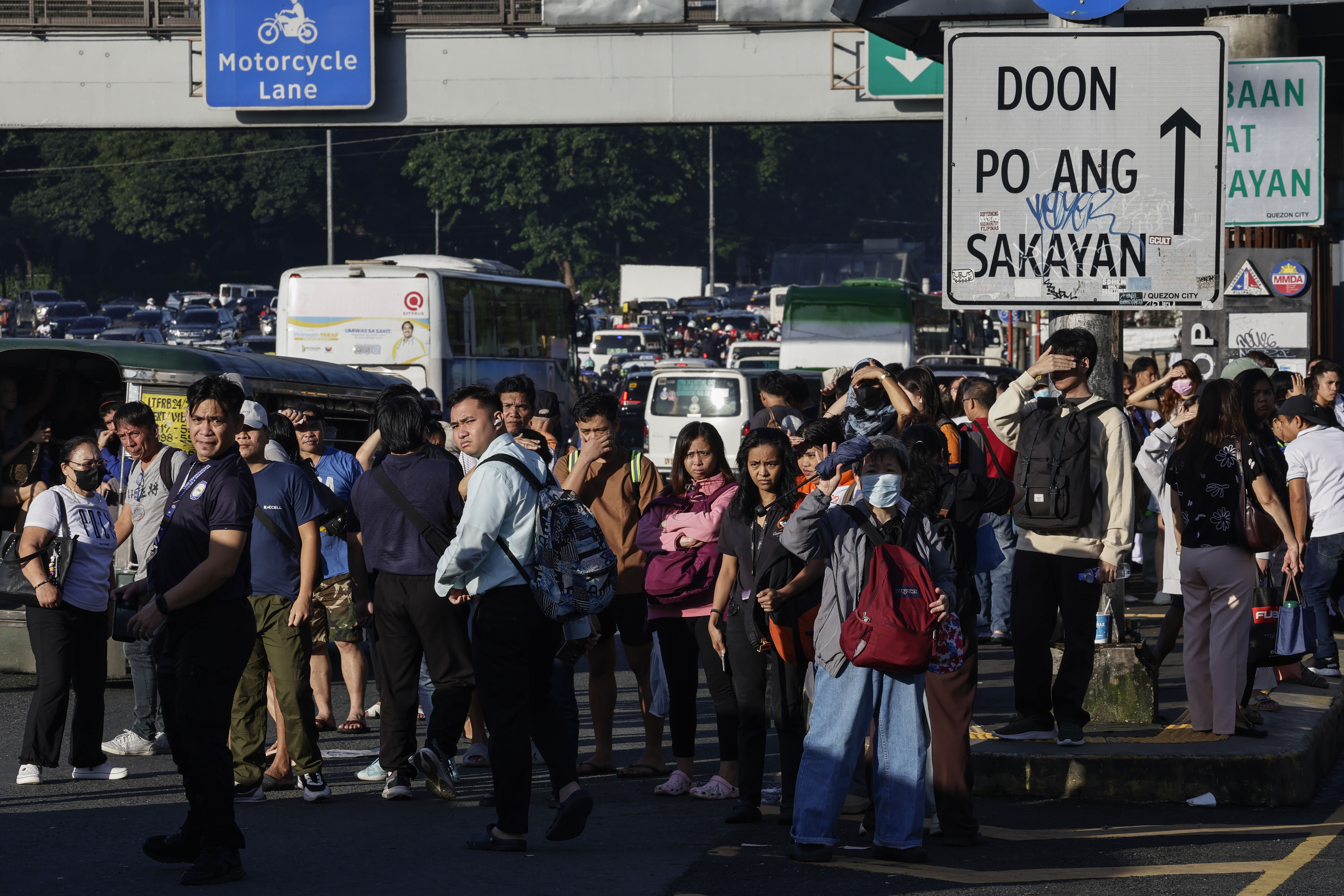 People wait at a transport stop in Quezon City, Metro Manila, Philippines