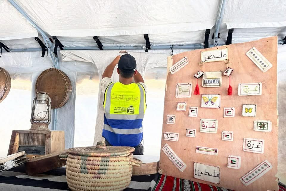 A specialist cataloging and documenting salvaged traditional metalwork and heritage items inside the temporary preventive conservation tent [Enas Naser/Al Jazeera]