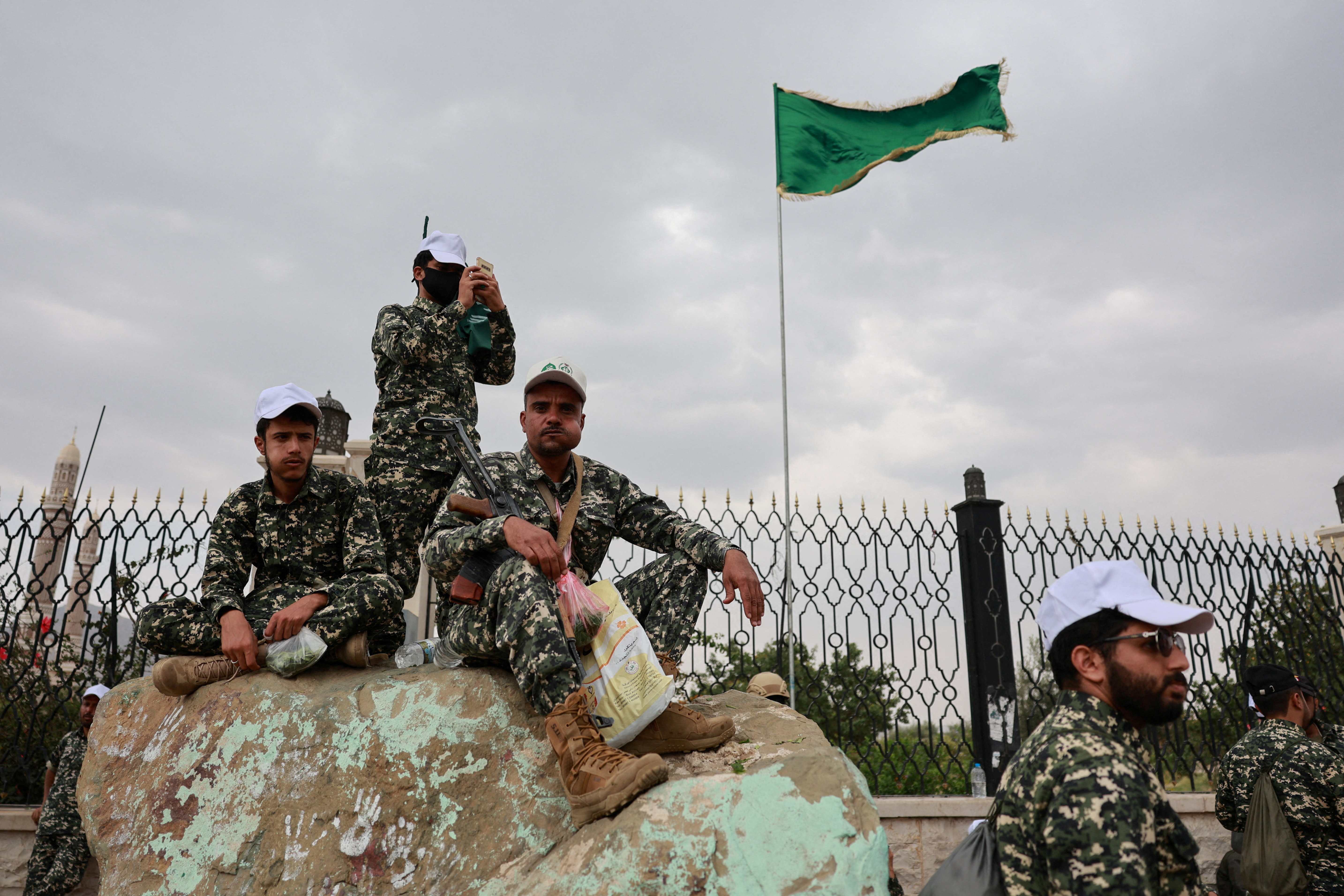 Members of Houthi security forces sit on a rock.