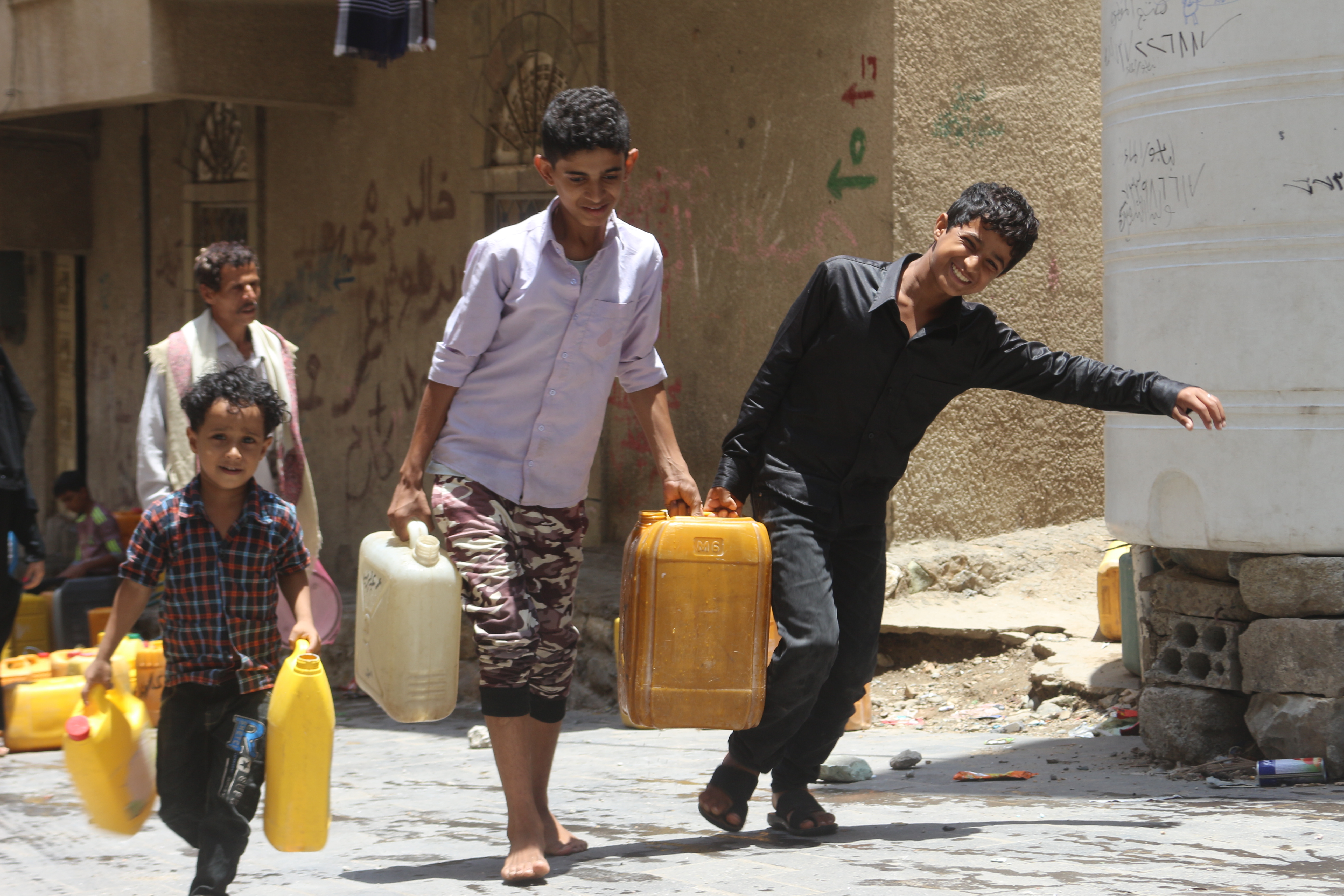 Children carry containers with water