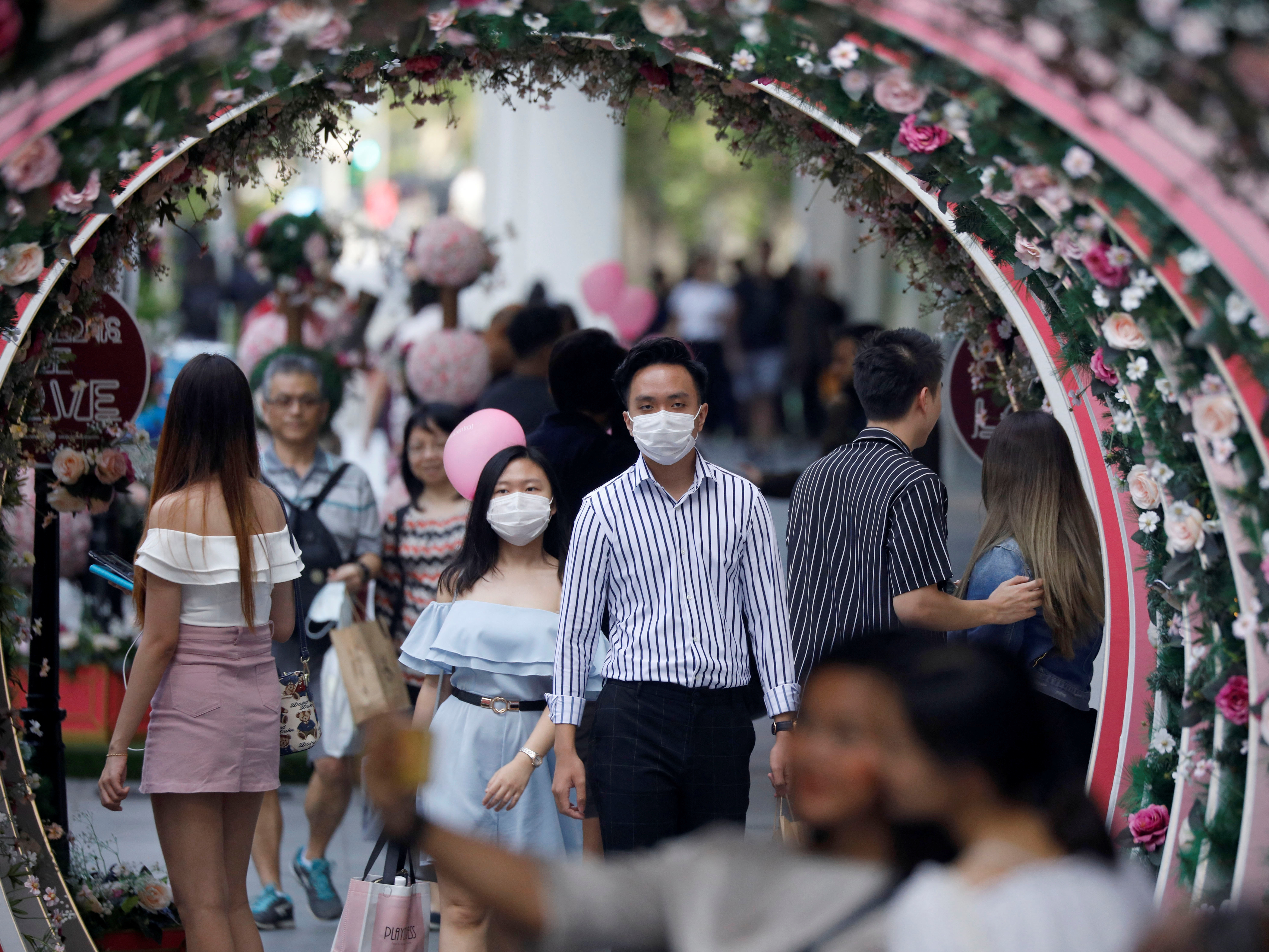 A couple celebrates Valentine’s Day as they wear face masks as a precaution against the COVID-19 outbreak at Orchard Road in Singapore on February 14, 2020
