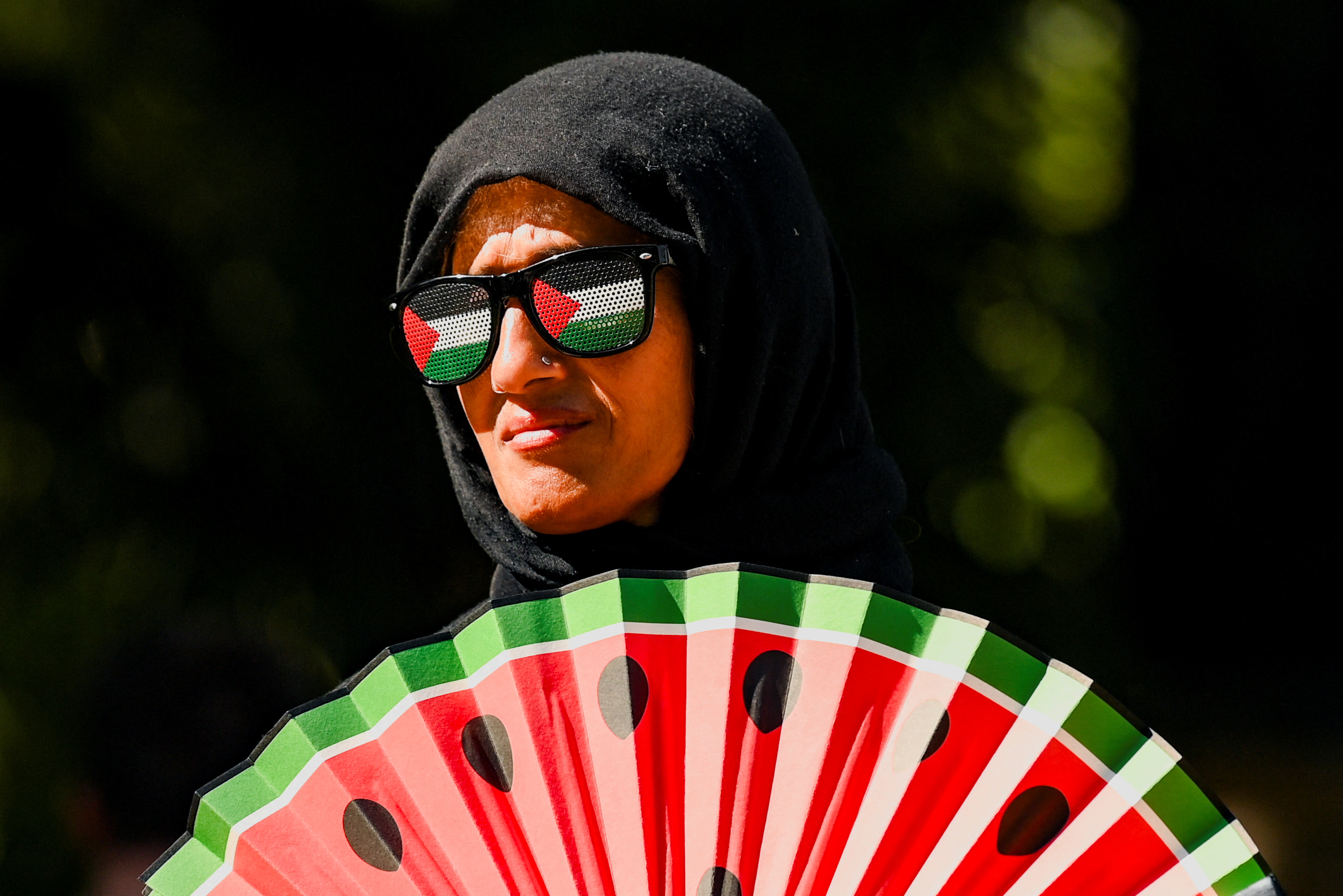 A protester wears eyewear in the colors of the Palestinian flag and holds a fan featuring a watermelon design during a rally organized by Defend Our Juries, challenging the British government's proscription of "Palestine Action" under anti-terrorism laws, in Parliament Square, London, Britain, August 9, 2025. REUTERS/Jaimi Joy TPX IMAGES OF THE DAY