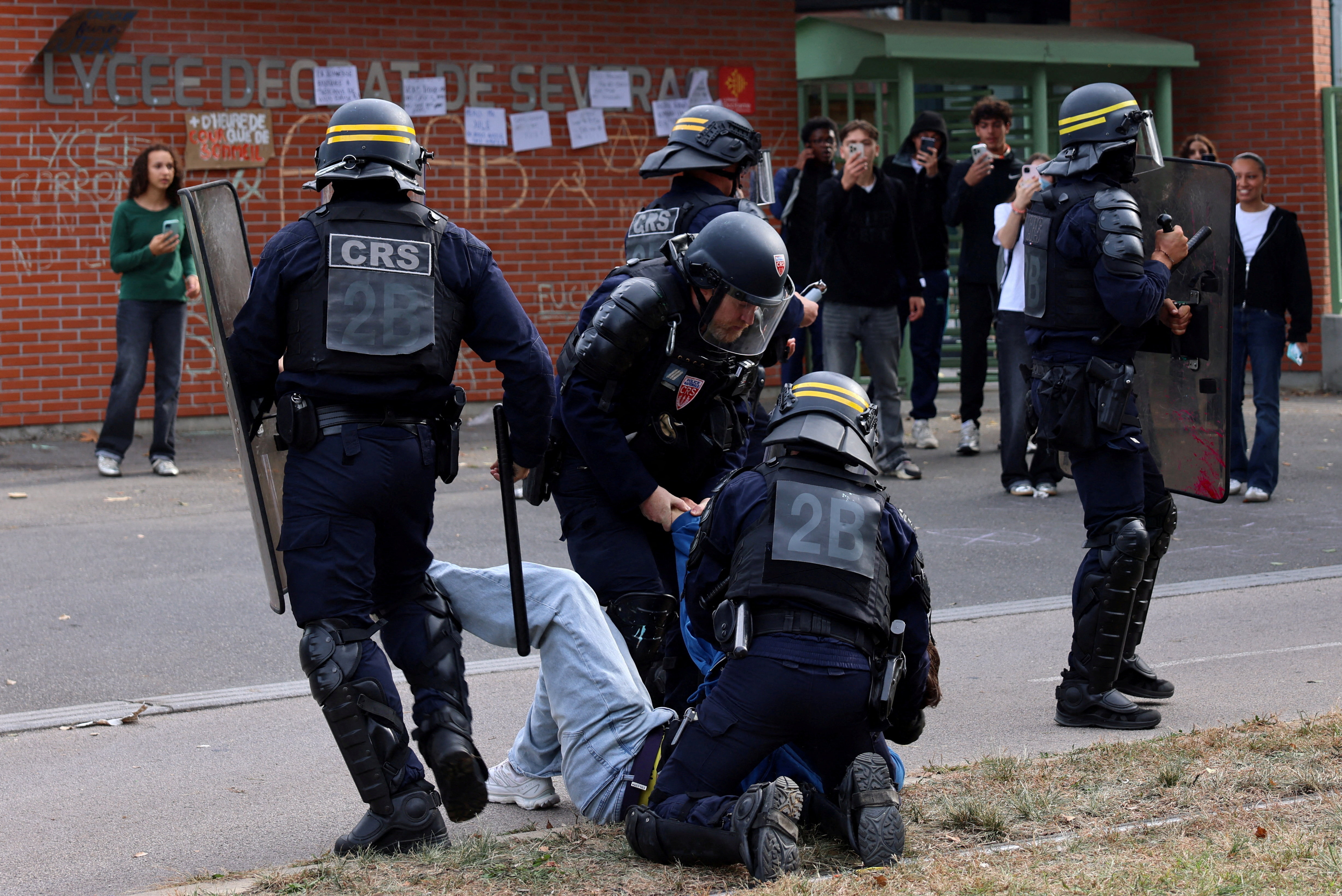 French CRS riot police apprehend a protester during clashes outside the Lycee Deodat-de-Severac high school as part of nationwide protests by high school students to demand the hiring of substitute teachers, increased resources and better learning conditions, in Toulouse as more than 400 schools remain closed following days of student protests that have escalated into violence in some places, France, October 2, 2026. REUTERS/Nacho Doce TPX IMAGES OF THE DAY