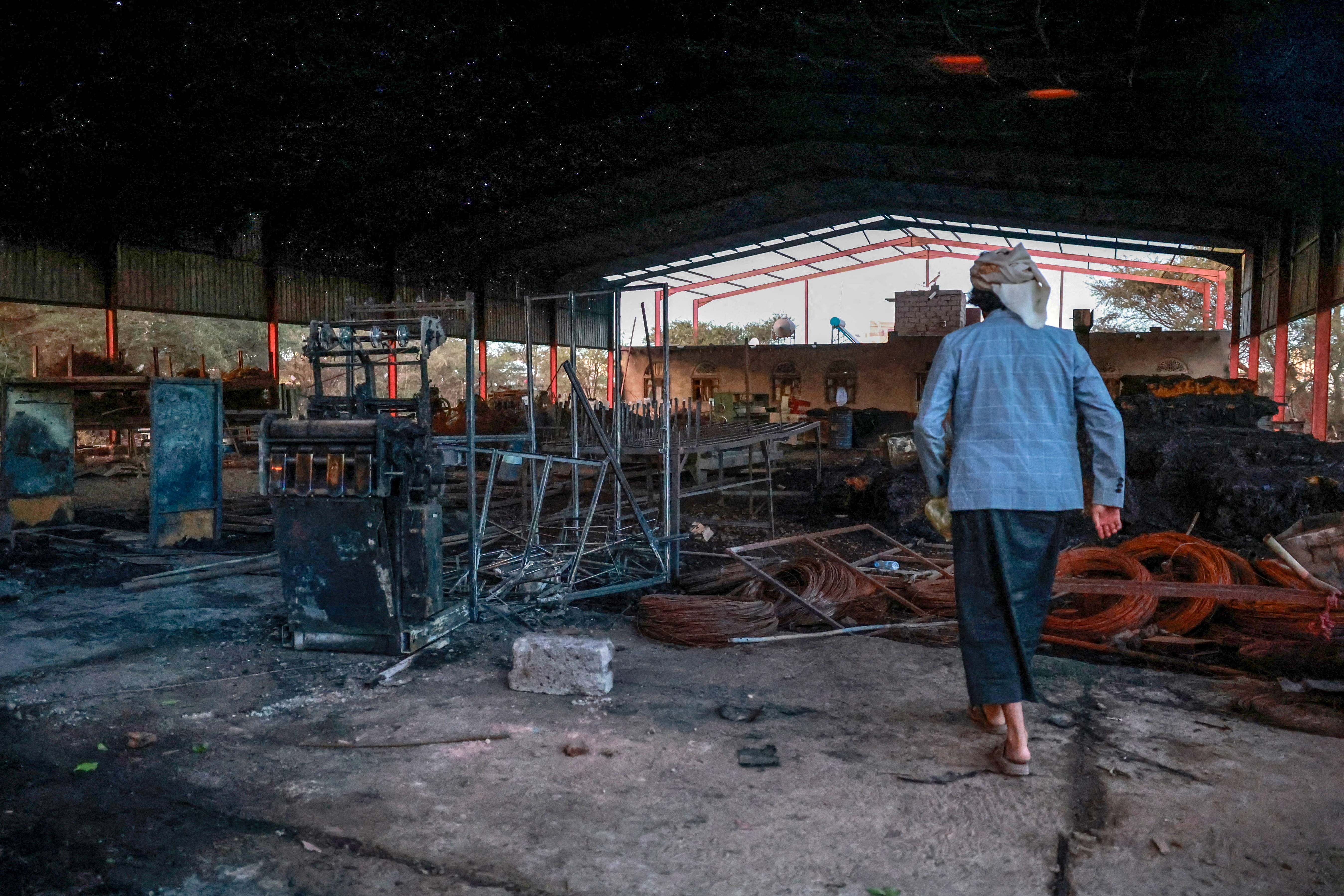 A man surveys damage at a factory hit by an airstrike in Sanaa, Yemen, October 4, 2026