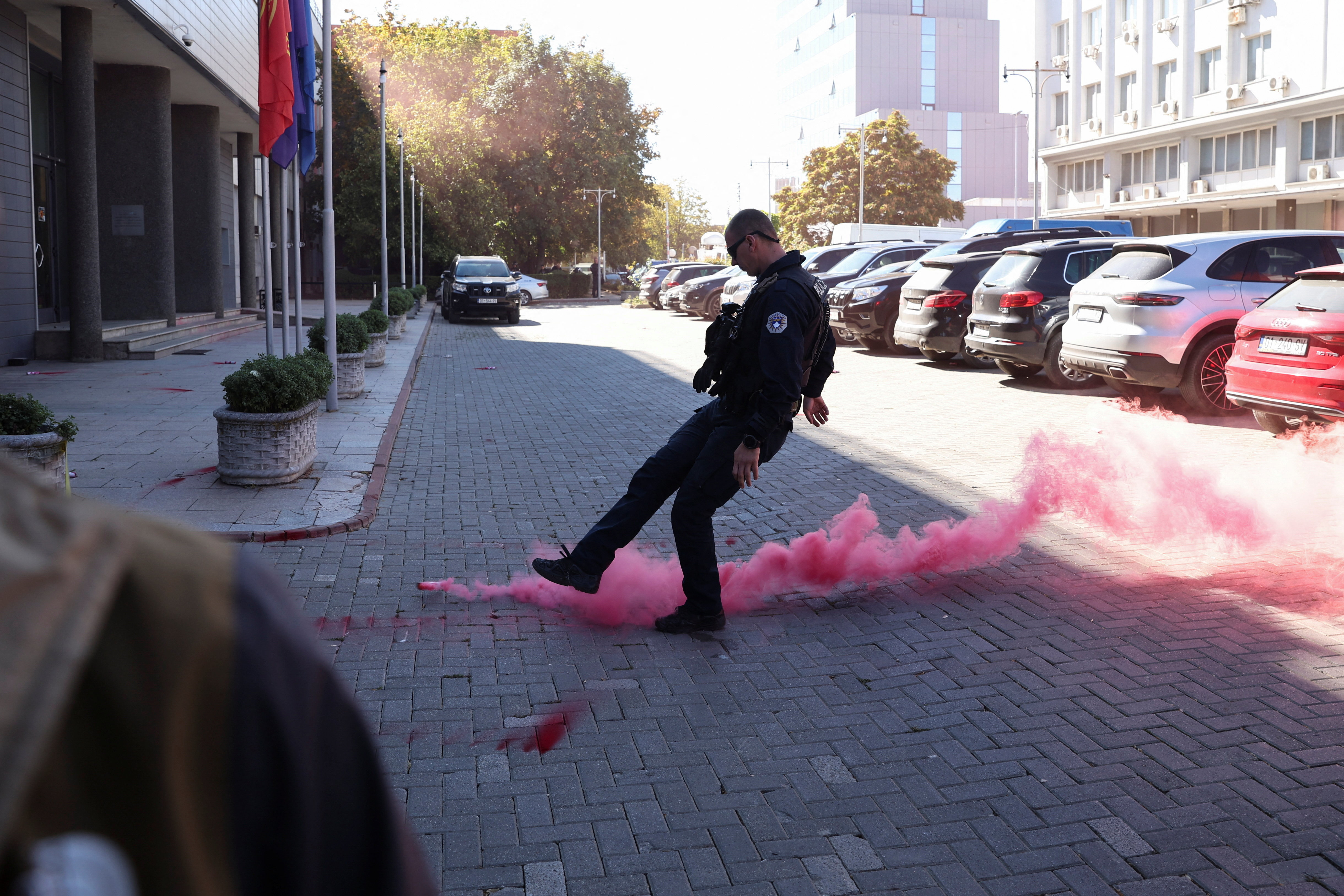 A Kosovo police officer kicks a flare near the parliament building during the extraordinary session to vote limiting the powers of the Hague-based war crimes court, weeks after it sentenced former president Hashim Thaci and other Kosovo Liberation Army (KLA) leaders to a combined 81 years in prison for war crimes, in Pristina, Kosovo, October 5, 2026. REUTERS/Valdrin Xhemaj