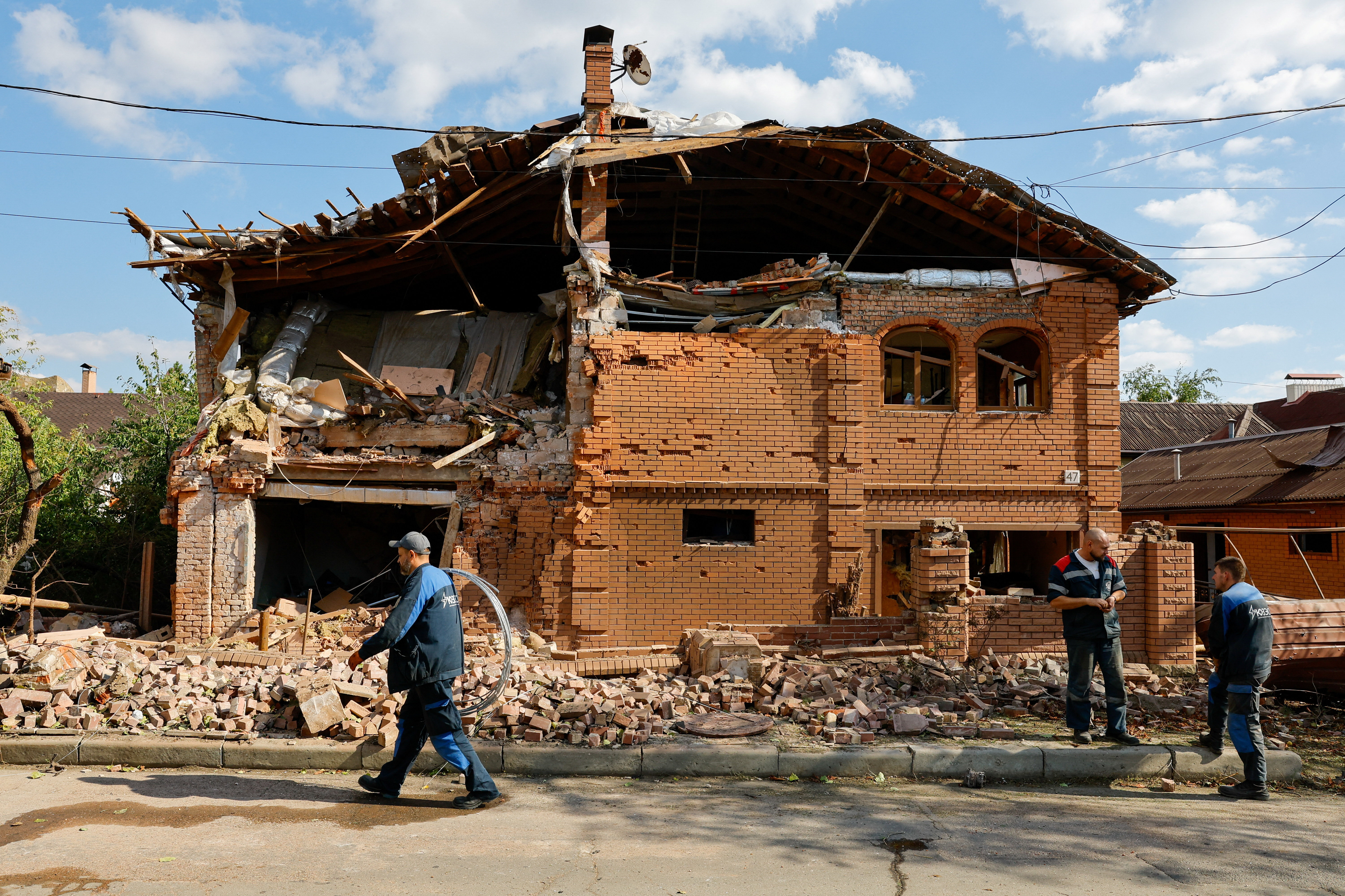 Workers gather near a destroyed residential building hit in Donetsk