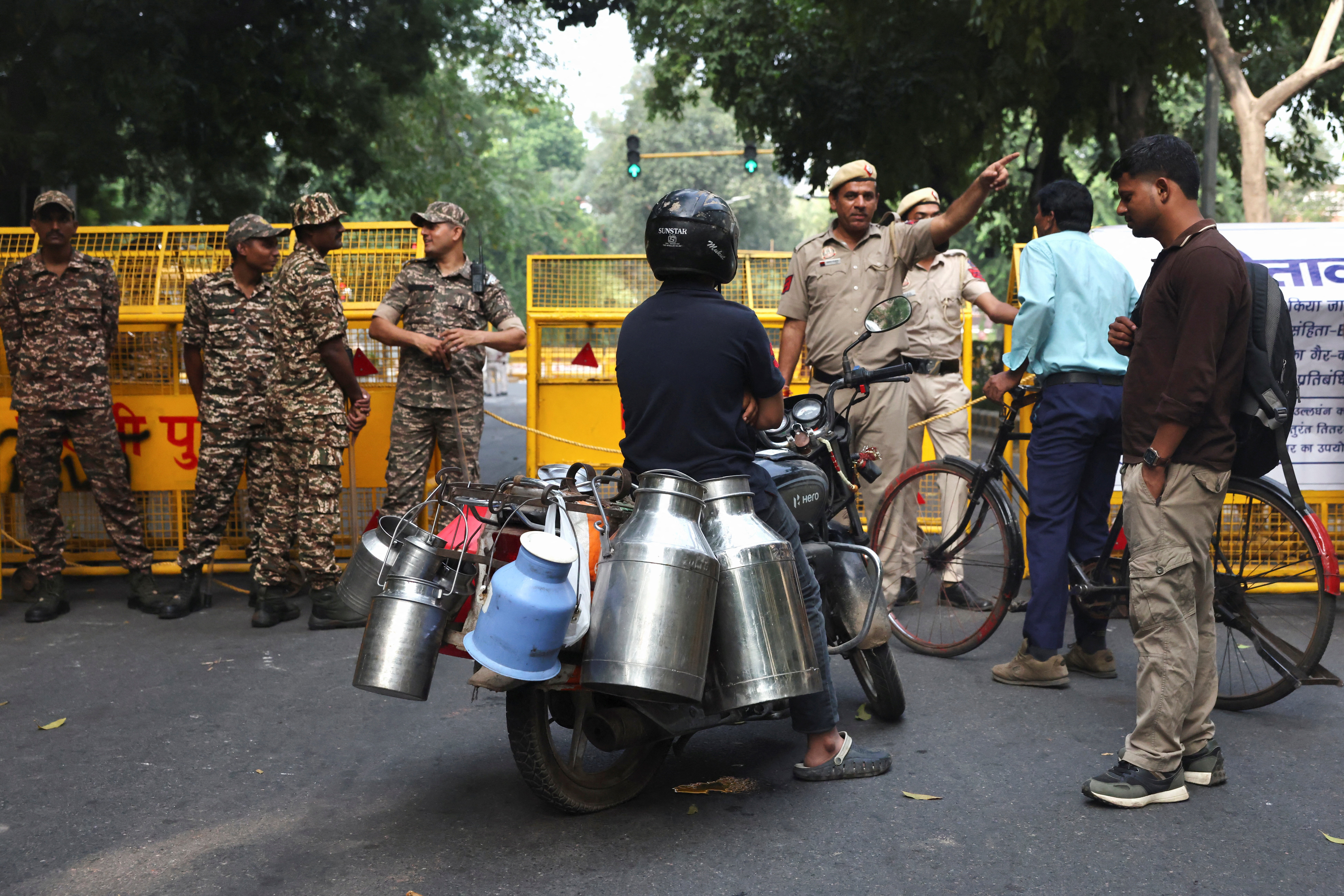 Police officers surrounded by yellow barricades direct commuters to an alternate route.