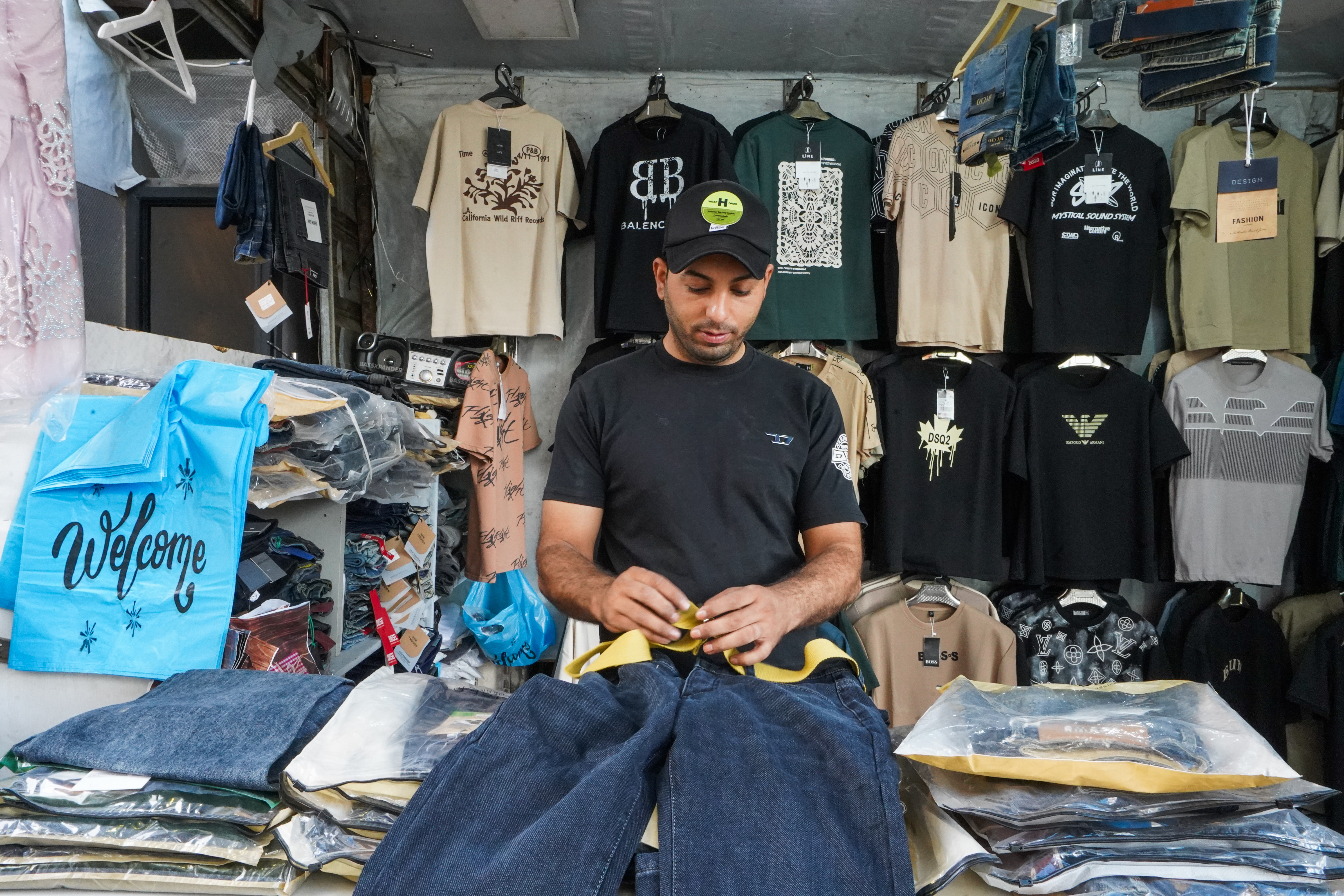 Merchant Khalil Al-Tahrawi displays clothing in a small tent by the roadside in the Nuseirat market after his shop was destroyed during the war October 6, 2026 [Iyad Al-Qatrawi/Al Jazeera]