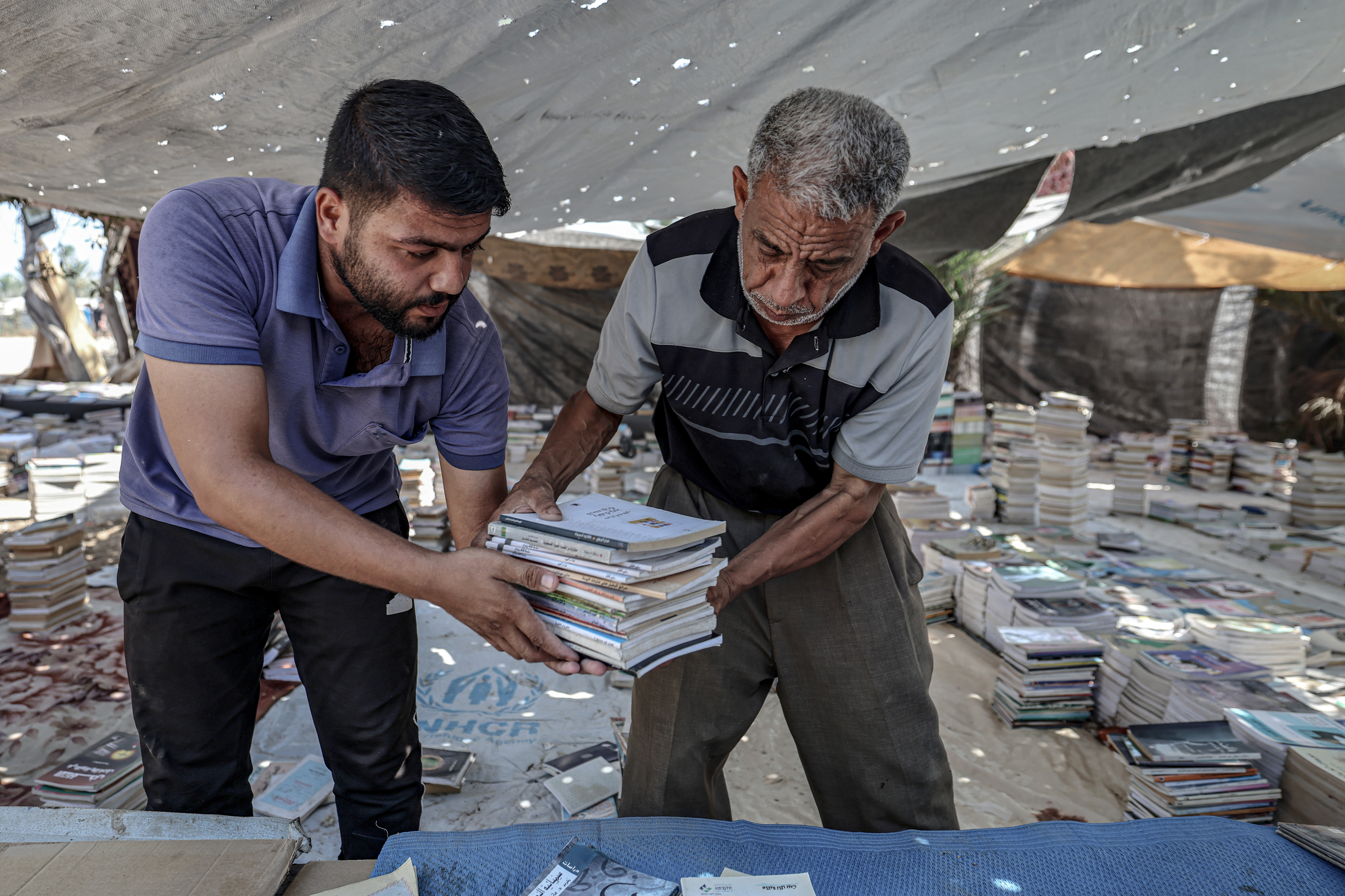 Mohammed Saad and his son sort and organise books in Deir al-Balah, Gaza