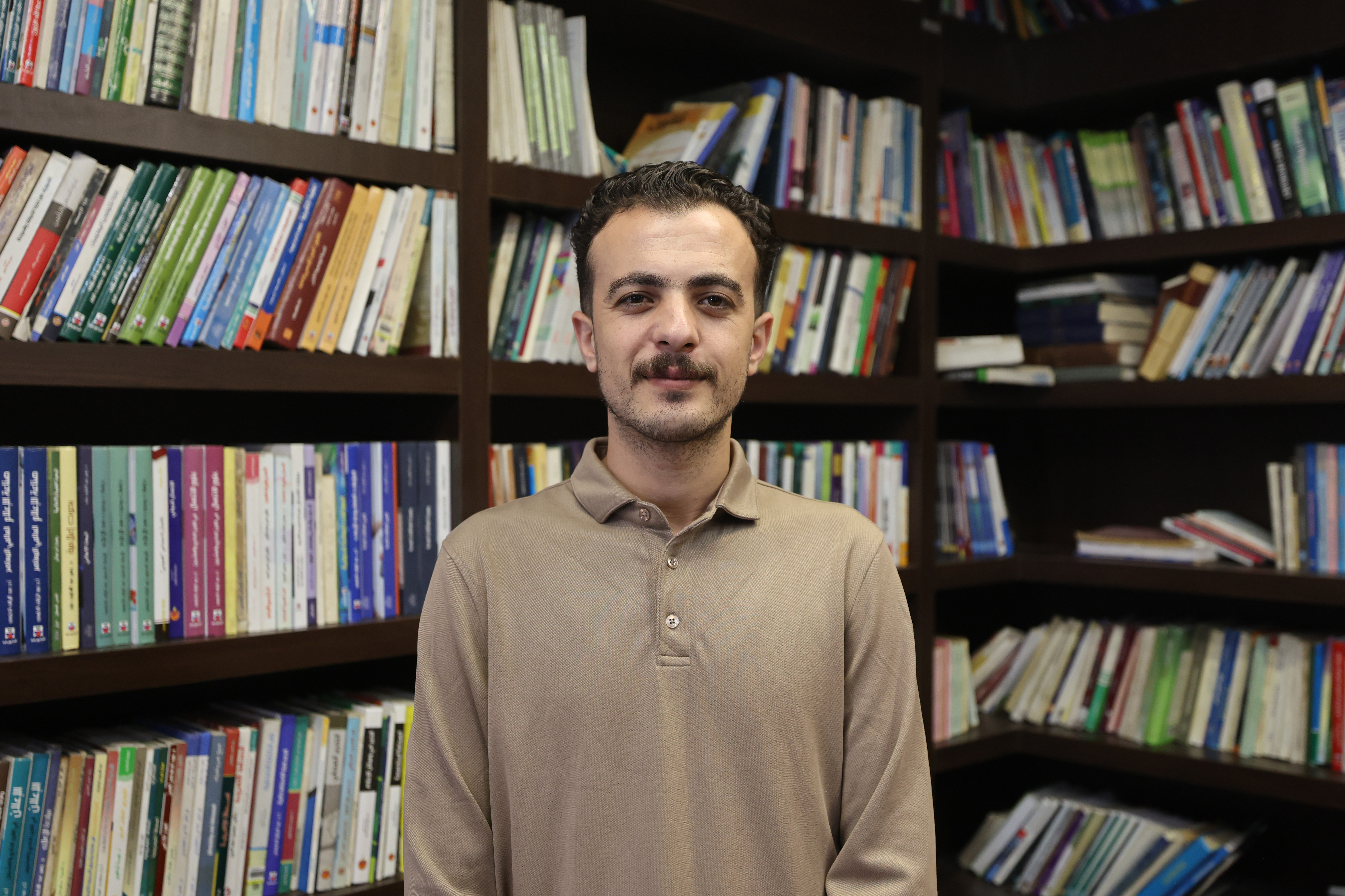 Omar Hamad, founder of Phoenix Library, stands among books rescued from libraries and homes across Gaza, preserving a collection that survived the devastation.