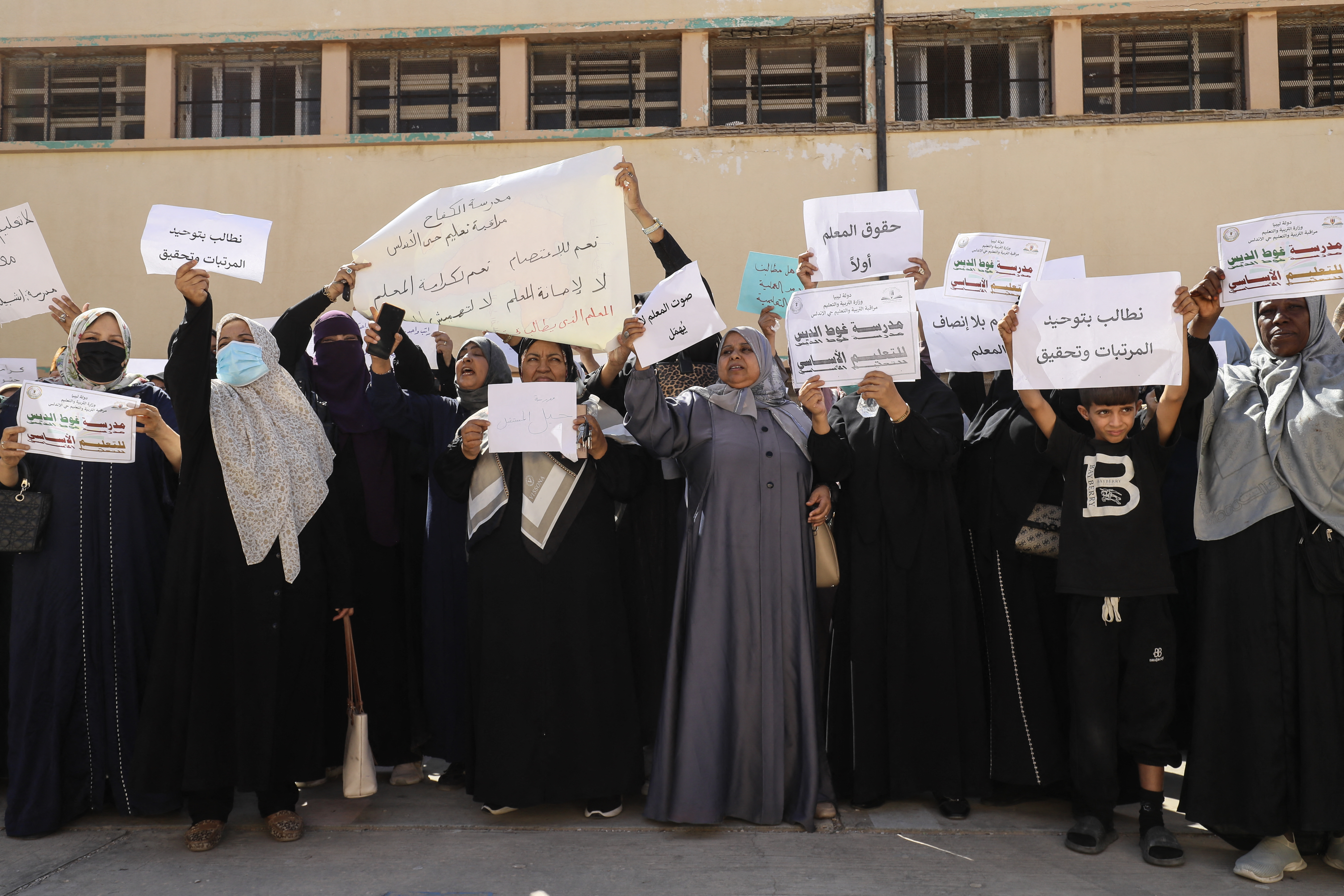 Teachers hold up placards during a demonstration demanding higher salaries and better working conditions at a school in Tripoli on September 29, 2026 [Photo by Mahmud Turkia / AFP]
