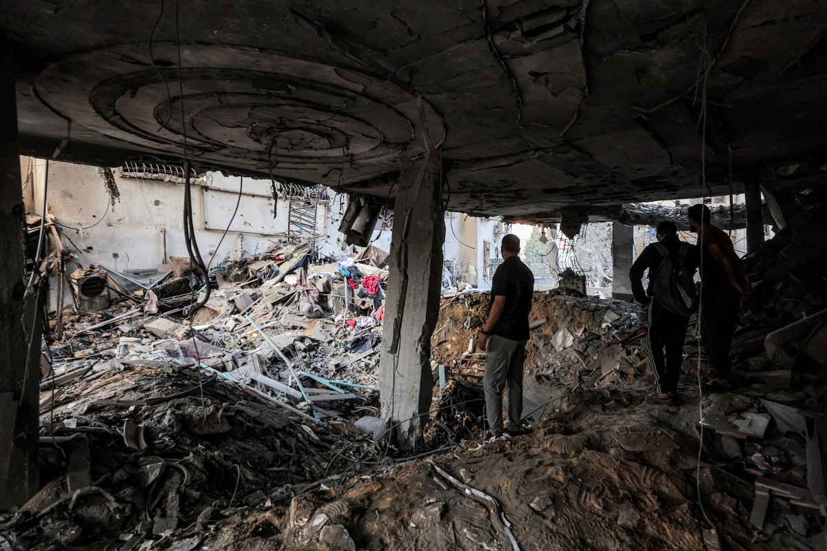 People inspect debris in a heavily-damaged building following an Israeli strike on a residential apartment in the Rimal neighbourhood of Gaza City