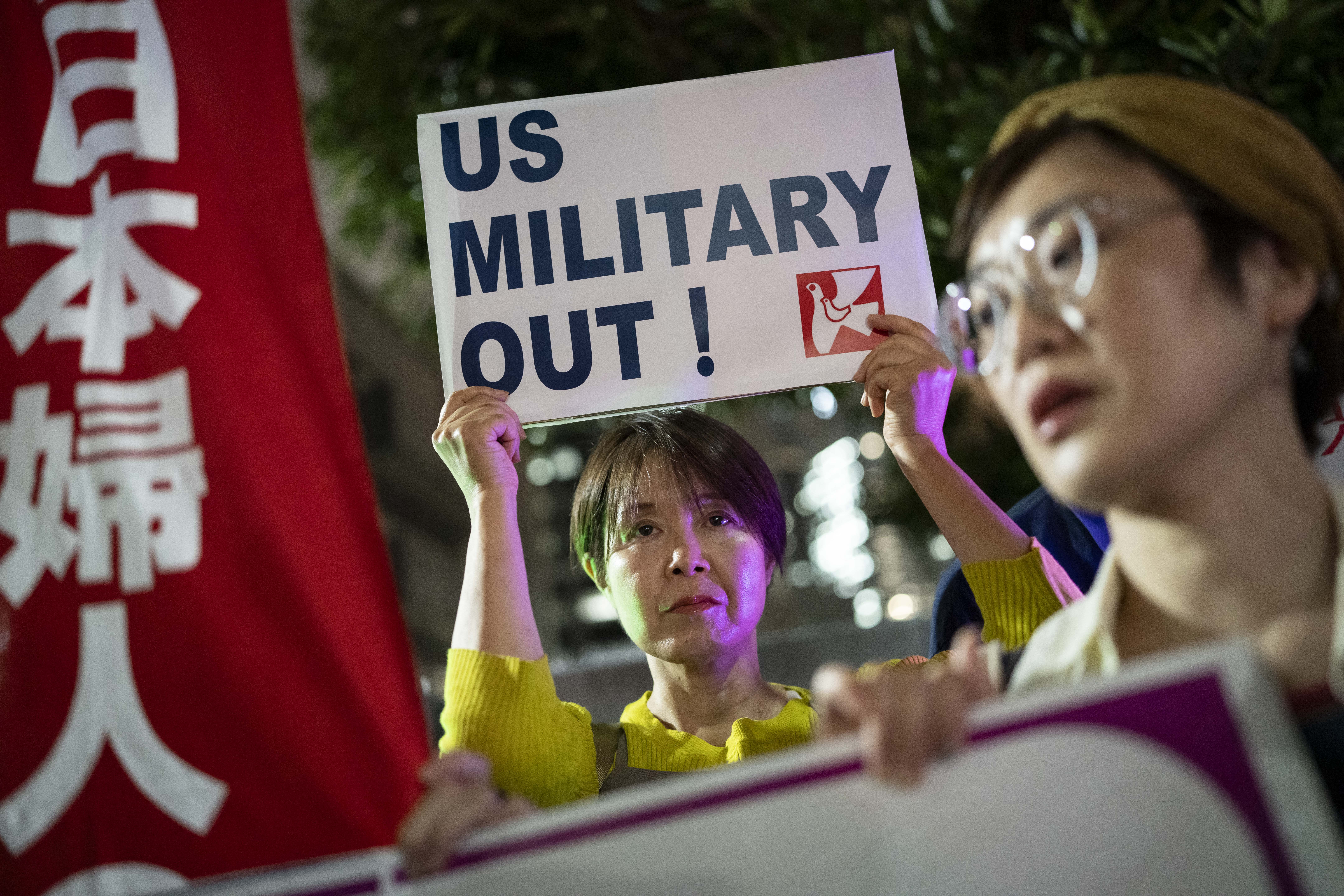 A woman holds up a placard reading 'US military out' during a protest against the killing of a woman in Okinawa allegedly committed by a US Marine Corps member